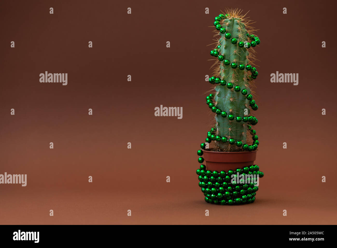 Cactus come albero di Natale con palla verde ghirlanda su sfondo browm. Natale e Anno Nuovo feste celebrazione del concetto. Parte anteriore Foto Stock