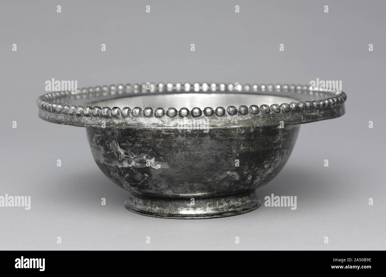 Ciotola con bordo svasato, 300-500. Questo recipiente è stato probabilmente destinate ad essere utilizzate in una casa privata, forse un elegante villa sulla costa mediterranea. Ricchi romani memorizzata una varietà di navi di argento e di attrezzature per il divertimento e ci siamo divertiti con loro mentre mangiare e bere a eventi sociali. Questa coppa è decorata con un bordo svasato, una caratteristica che spesso si trova su nazionale ciotole d'argento di questo periodo. La forma base è stata formata prima mediante martellatura. Poi il recipiente è stato lucidato e inseguiti mentre è ruotata su un tornio. La decorazione a perline è stata ottenuta mediante martellatura l'argento in uno stampo. Foto Stock