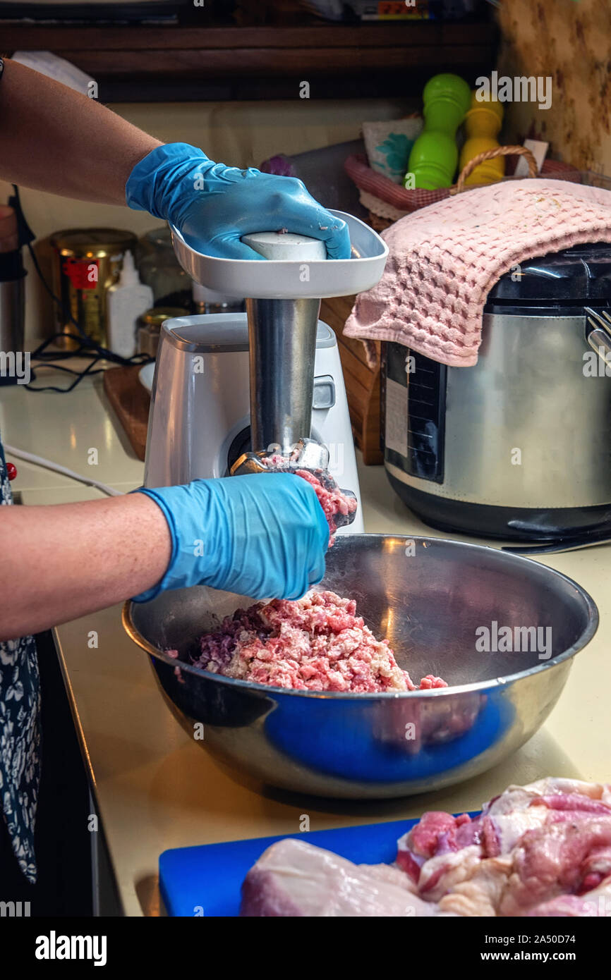 Cuocere rende fresca macinata di carne in un tritacarne. Il processo di macinazione delle carni in una caffetteria. Foto Stock
