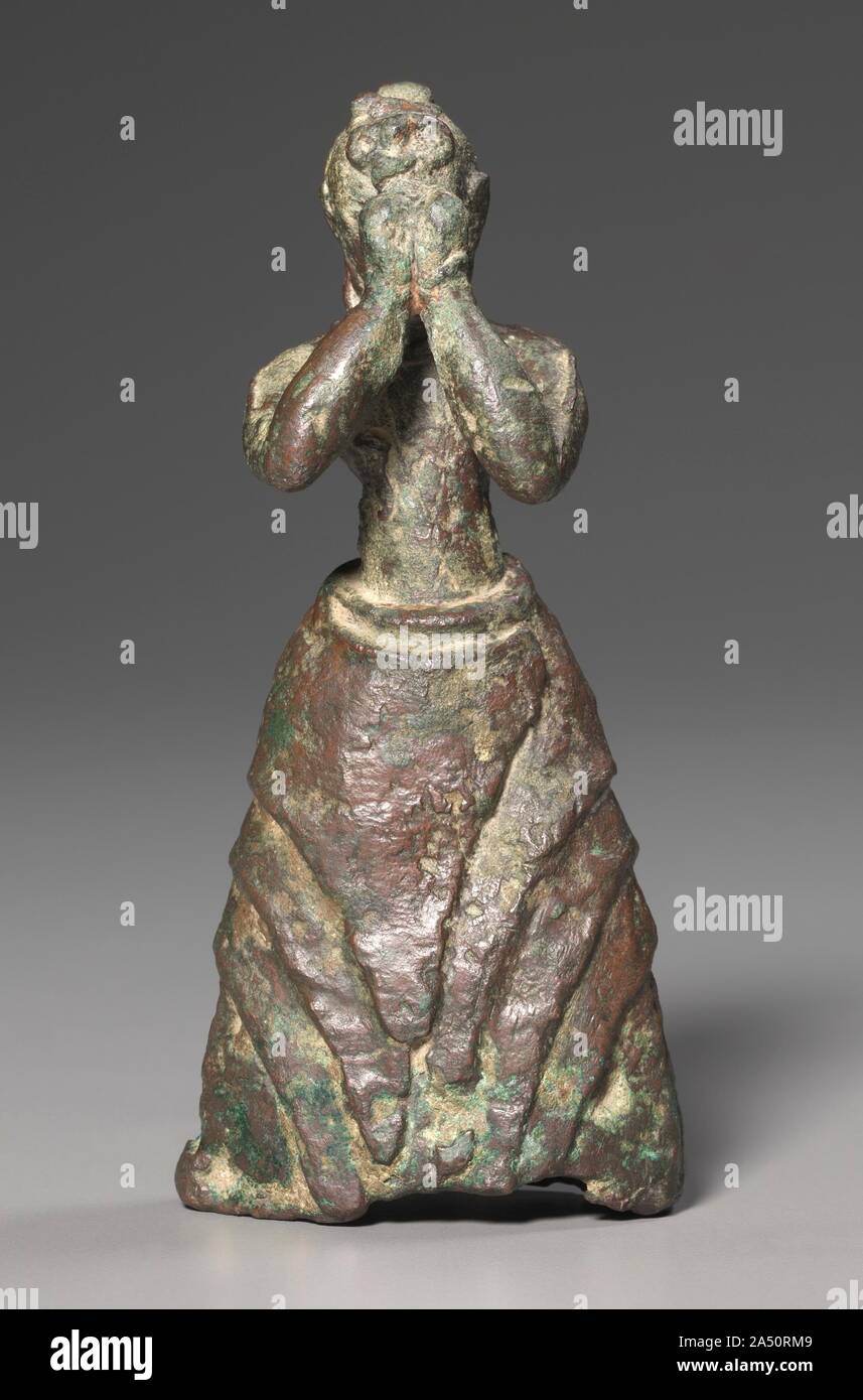 Adoratore femmina, c. 1600-1500 A.C. Questo estremamente rare Minoan statuetta in bronzo rappresenta una ragazza di adorare una divinità. Probabilmente è stato lasciato come una dedizione a una divinità. Indossa un mantello flounced sopra una tunica con maniche frontalmente aperto. La figura mostra un notevole grado di dettaglio, compresi avvolta ad anello orecchini, bracciali e una collana. La sua acconciatura rasata, non trovato su qualsiasi altra Minoan statuetta in bronzo, corrisponda a quello delle figure dipinte in contemporanea grossolanamente affreschi scoperti sull isola di Thera, a nord di Creta. La sua ottima condizione, rarità, dettagli e proporzioni equilibrate impostato Foto Stock