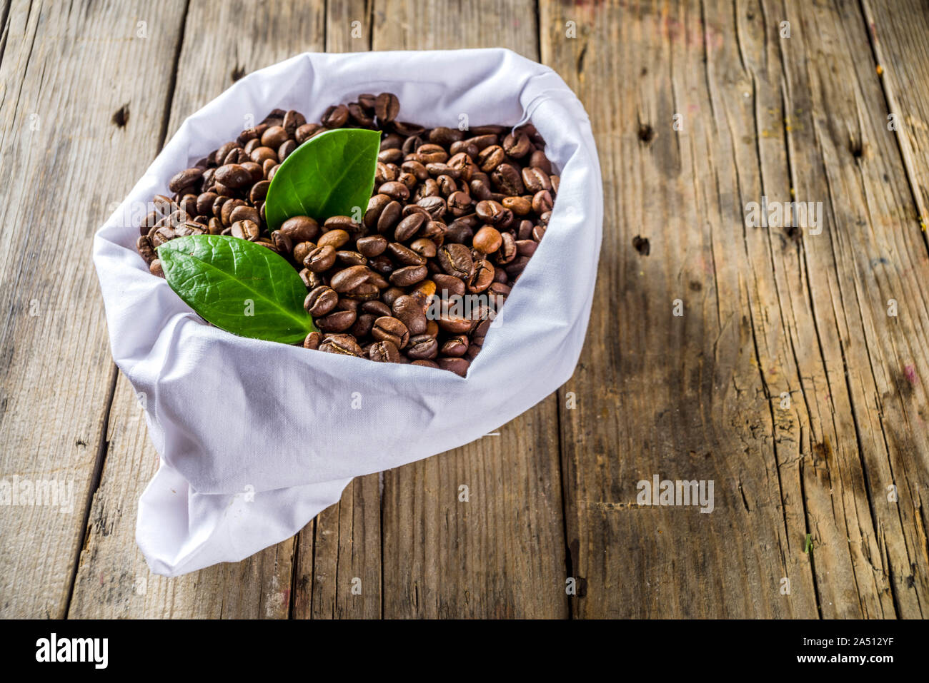 Tazza di caffè espresso con i chicchi di caffè. Il caffè macinato e foglie su sfondo rustico Foto Stock