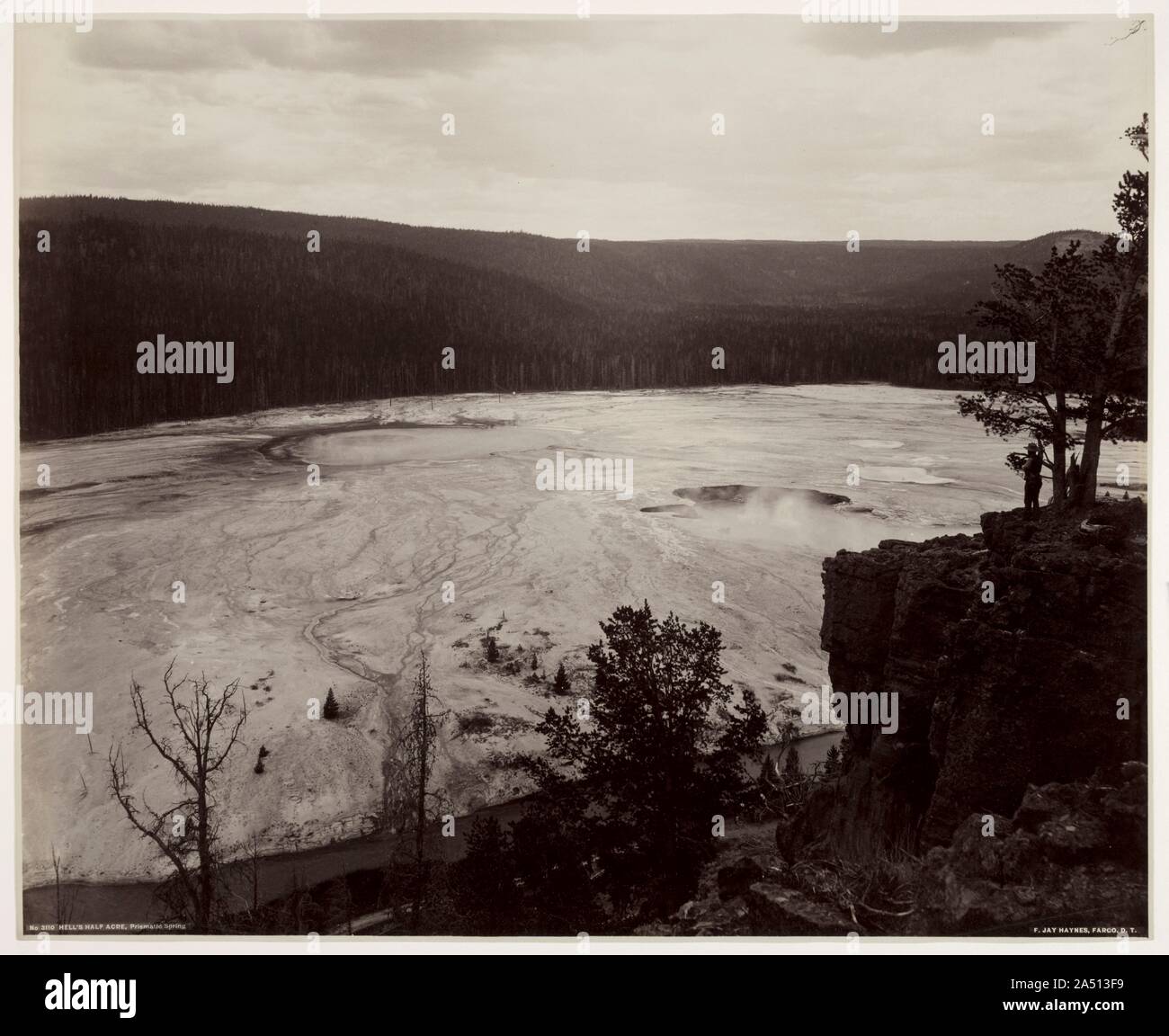 Hell's Half Acre, prismatico molle, c. tardo 1880. Frank Jay Haynes era un fotografo della vita nell'Ovest americano e dei primi giorni del Parco Nazionale di Yellowstone. Arrivando a Yellowstone nel 1880, ha accompagnato le spedizioni nel parco, che serve come fotografo ufficiale. Dal fondo del canyon per picchi di montagna, Haynes ha preso le sue fotocamere a posizioni dove ha potuto acquisire unici e vedute artistiche. In questa fotografia, egli ha documentato l'immenso spazio del paesaggio, reso particolarmente evidente dall'inclusione di una piccola figura permanente sulla scogliera a destra. Foto Stock