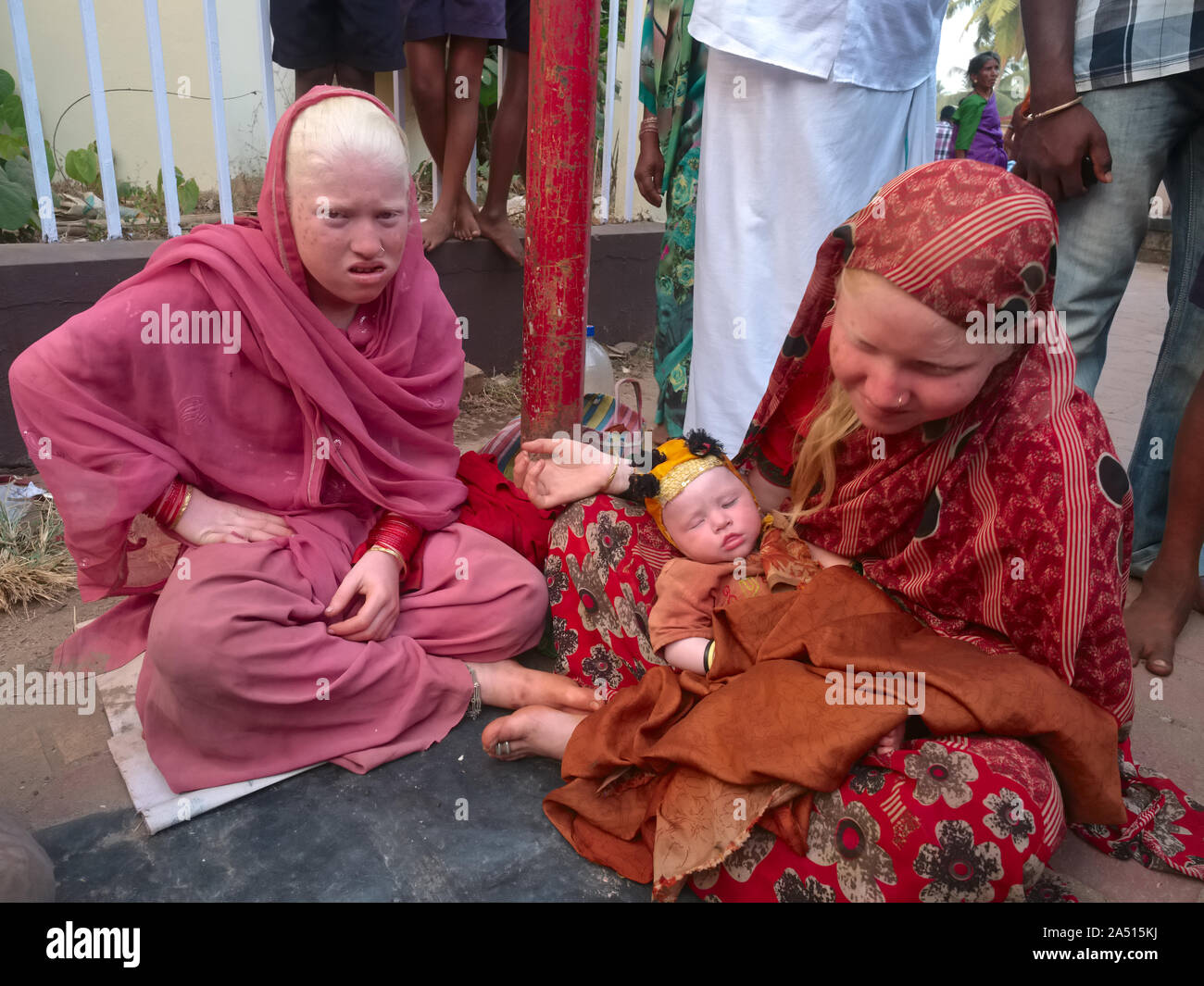 I membri di un indiano estesa famiglia Albini, due donne e un bambino, richiedono donazioni in Udipi, Karnataka, India, circondato da gente curiosa Foto Stock