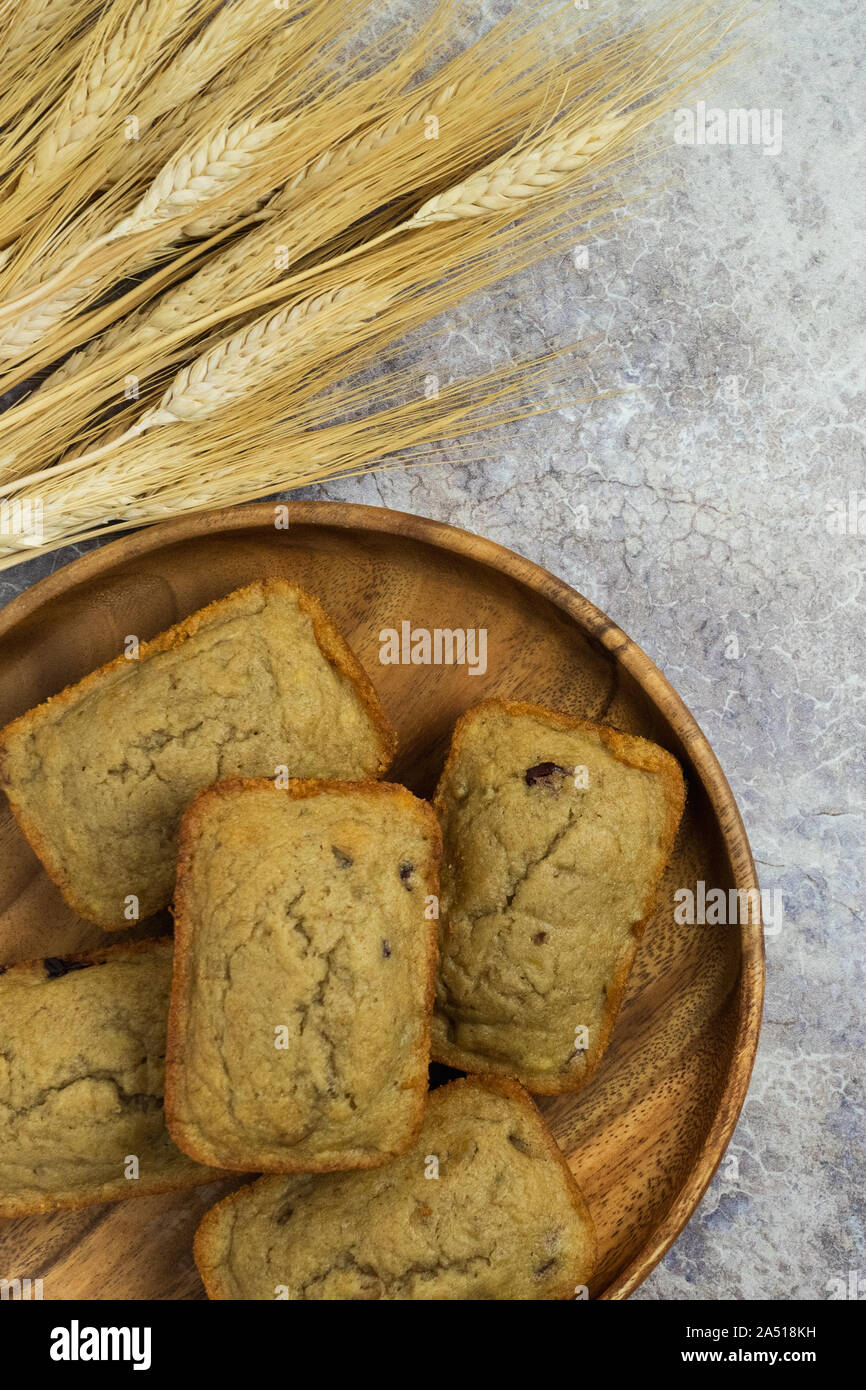 Mini verticale focaccia muffin su un vassoio di legno con covoni di grano su un bancone di marmo Foto Stock