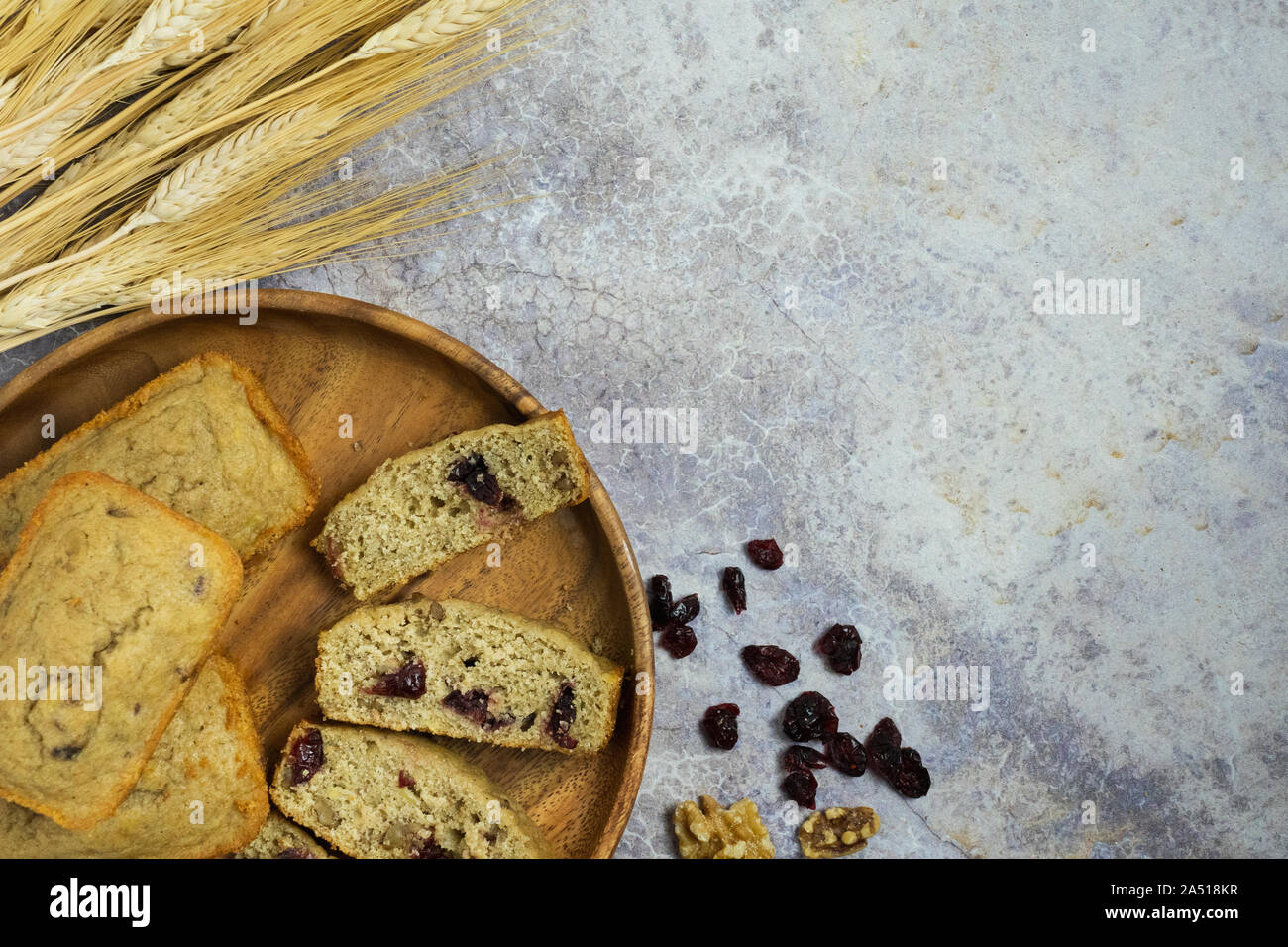 Mini pirottini di pani con un affettato su un vassoio di legno con covoni di grano e di mirtilli e noci su un bancone di marmo Foto Stock