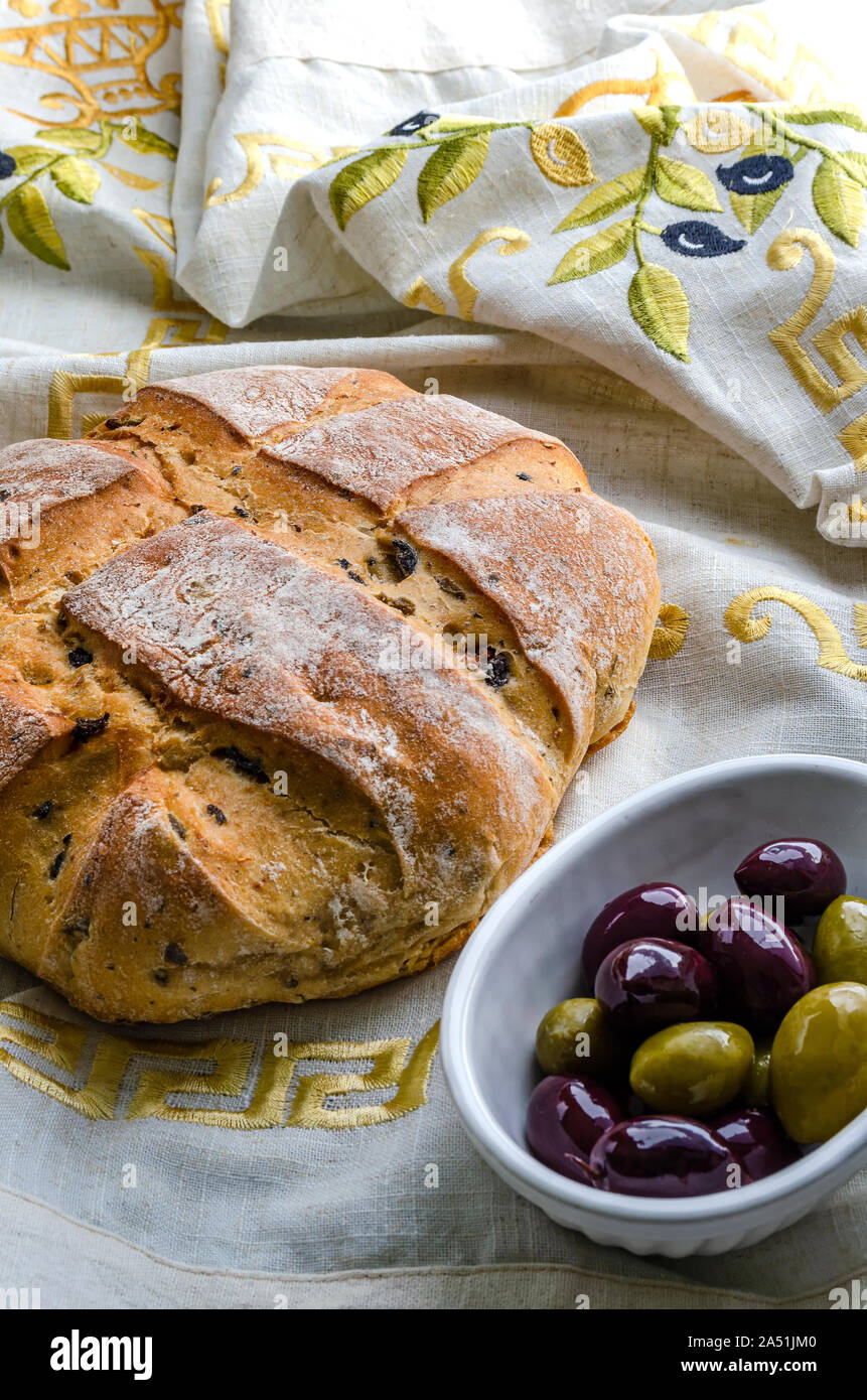 Un filone di oliva presi direttamente dal forno con un piatto di olive nere e verdi. Foto Stock