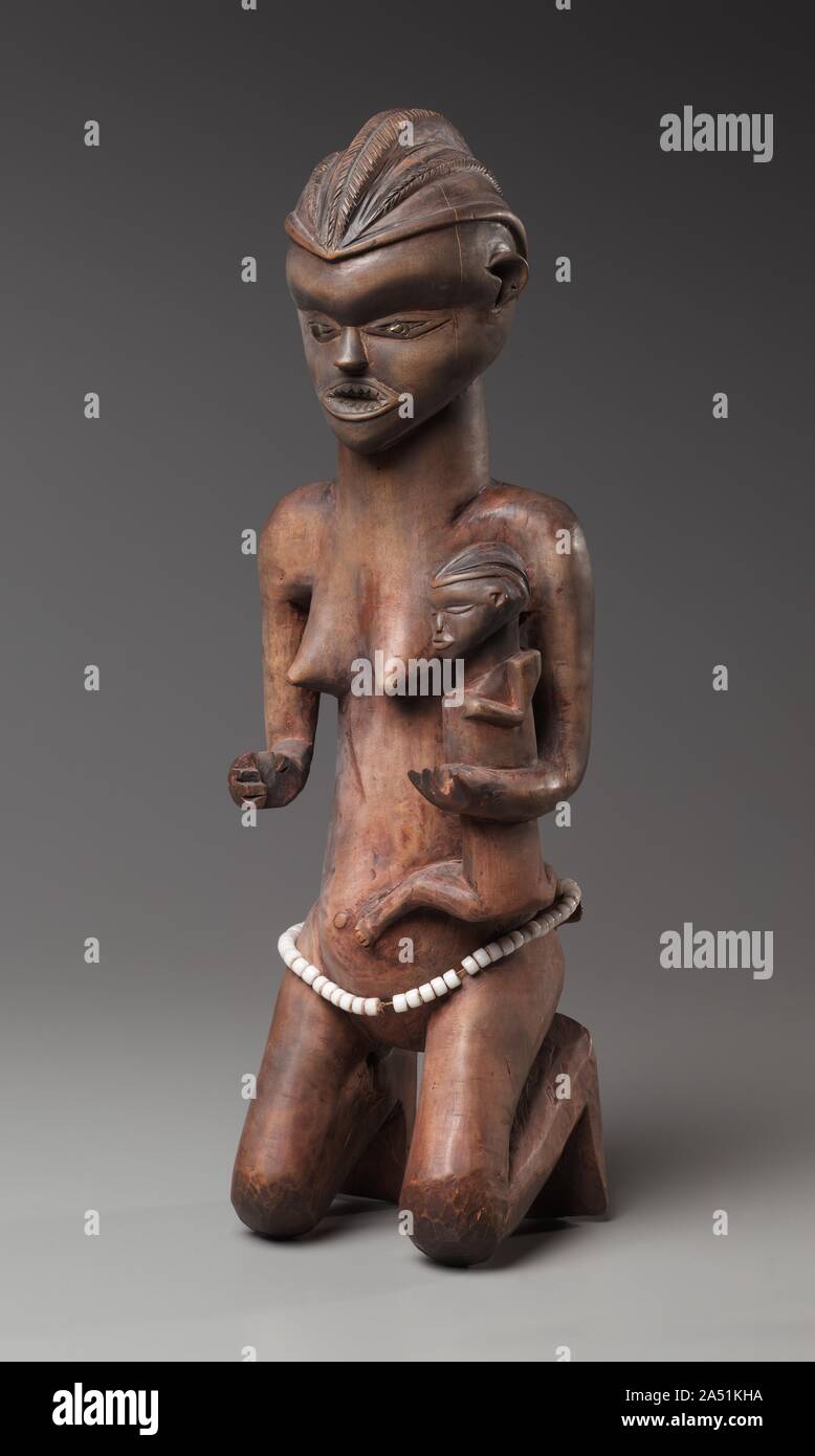 Madre-bambino la figura, 1800s-primi 1900s. Indossa un elaborato copricapo lobati e innervato waistbelt, e dopo aver presentato i denti e rosso in polvere di pelle, questa maternità figura sembra una volta hanno portato un'ascia e una tazza, imitazioni di legno dei due più importanti soprattutto gli attributi. Forse insieme con una controparte maschile è stato tenuto nascosto all'interno della casa rituale, che serve come un custode del chief&#x2019;s tesoro. Il suo stile e la colloca nel angolo occidentale di Pendeland, tra la Lutshima e Kwilu fiumi. Foto Stock