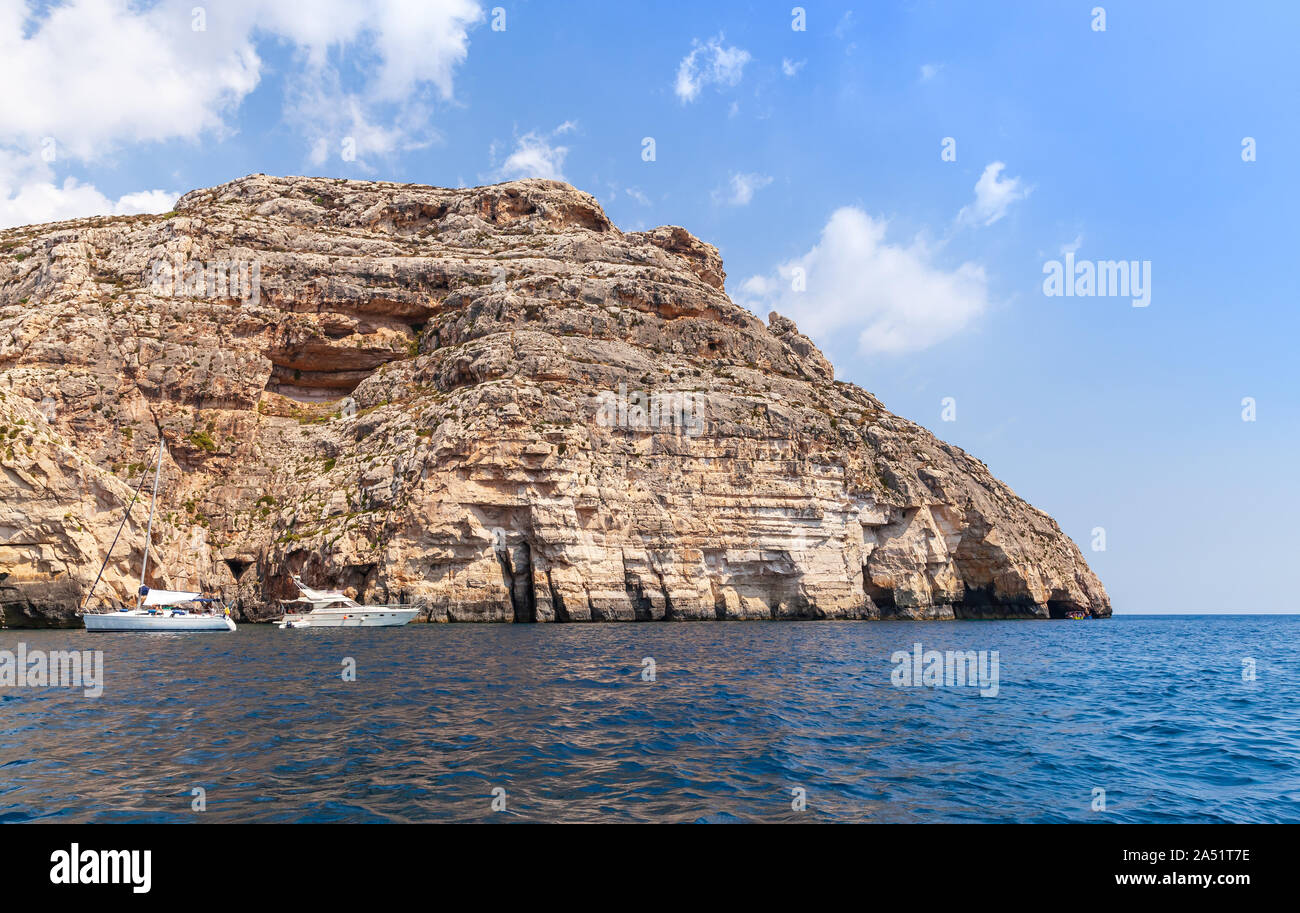 New Scenic 5 posti il paesaggio costiero con rocce rosse, yachts e acqua di mare al giorno d'estate e di sole al Blue Grotto, isola di Malta Foto Stock
