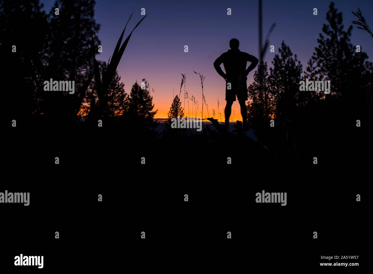 Un uomo si prende una pausa da un run e orologi al tramonto Foto Stock