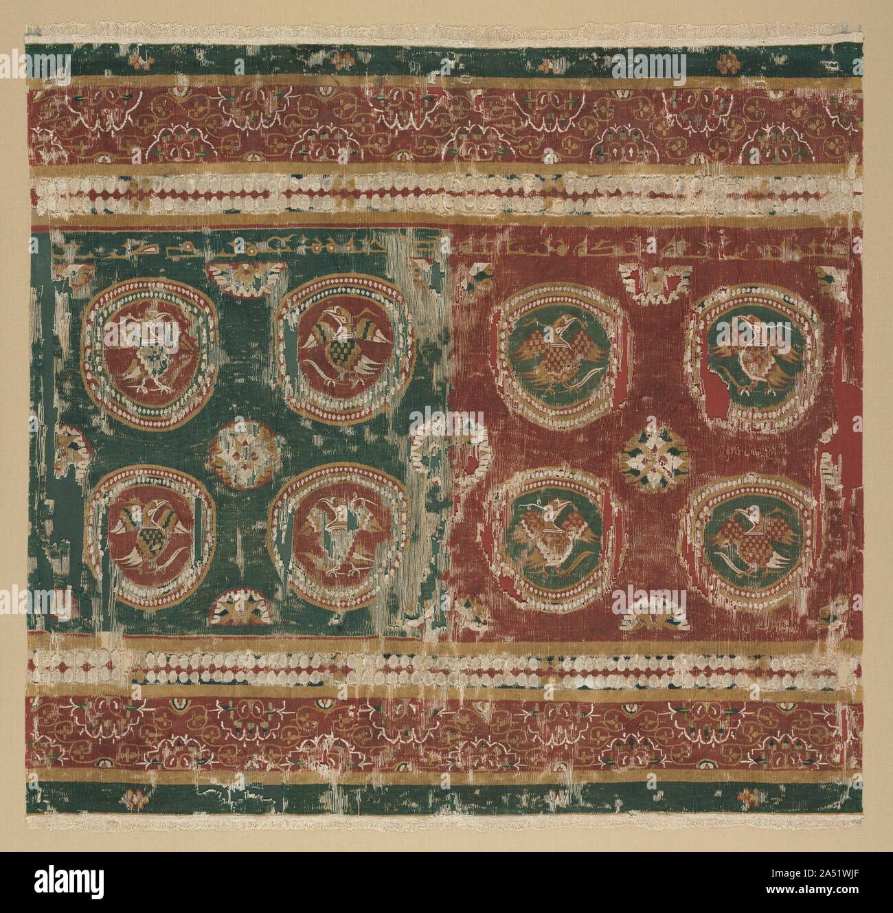 Federa del cuscino con iscrizione araba, 800s. Questo raro egiziano completo federa del cuscino è un capolavoro di colori contrastanti. Crimson e blu-verde lana si alternano nel terreno e bird abitata roundels, supportato da mostarda colorati di lana e lino non tinta tessuto tappezzeria in tessuto. Quando è ripiegato verso il basso al centro, sulla base di esempi da sepolture egiziano, quattro uccelli formano una unità su ogni lato e sono opportunamente crescente in volo. Al di sopra di un testo arabo scritto in kufic angolare script legge, "nel nome di Dio. La benedizione di Dio per il suo proprietario. Di che cosa è stato fatto in tiraz." La parola ti Foto Stock