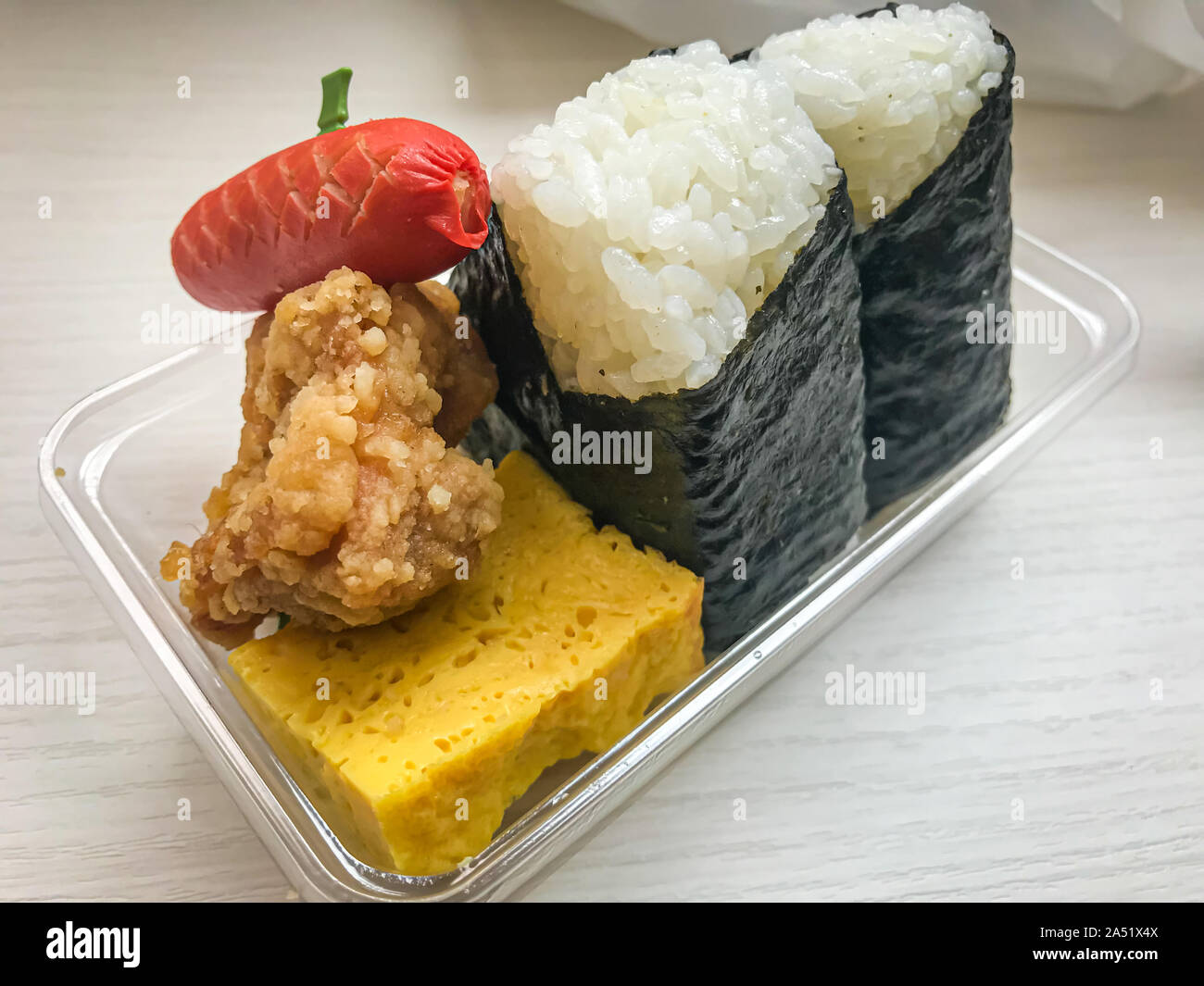 Giapponese fast food, due rotoli di sushi, un mini salsiccia, uova e pollo Foto Stock