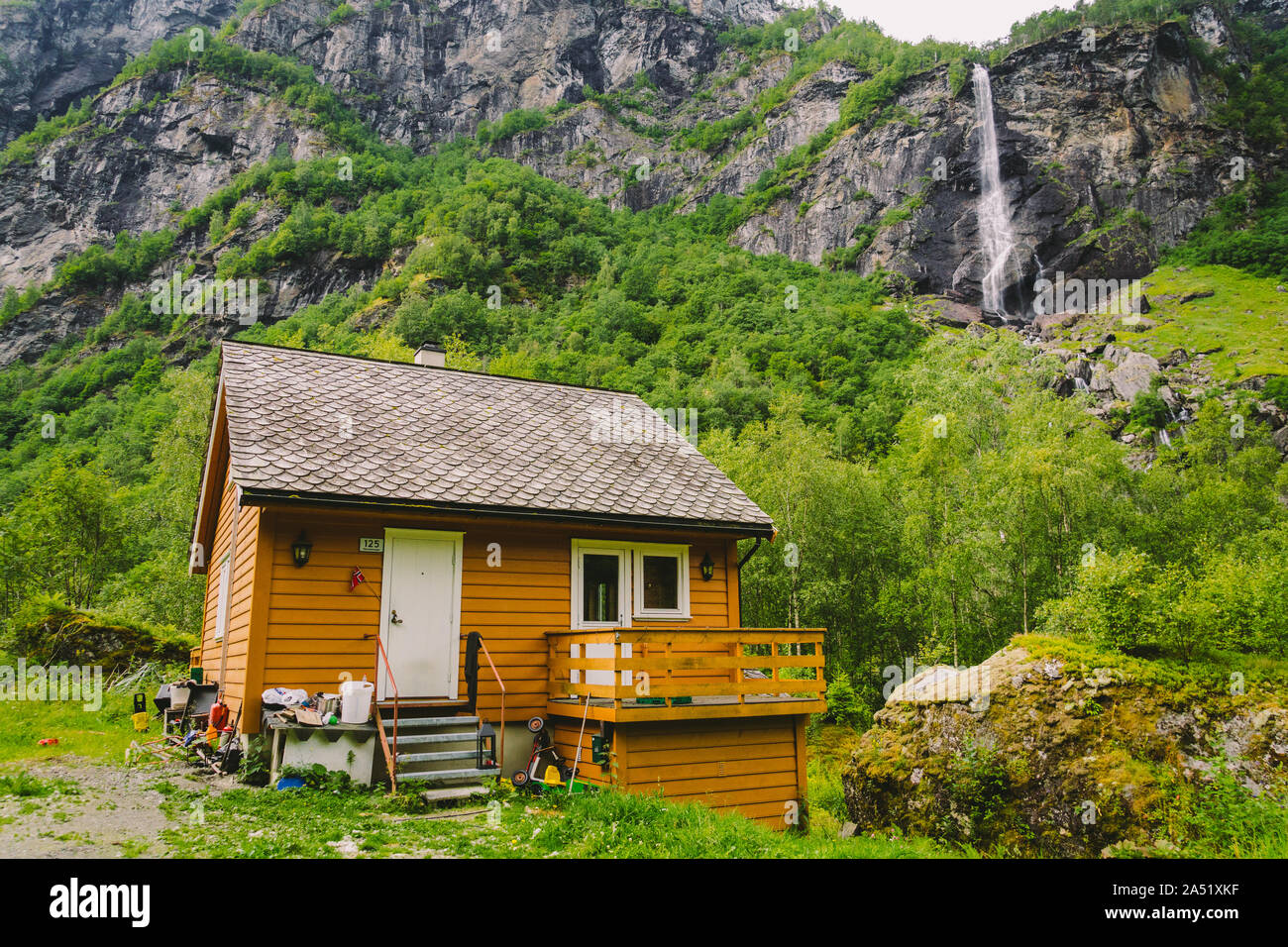 Casa rurale vicino a cascata e montagna in città flam Norvegia settentrionale. Casa e cascata. Norwagian tradizionale casa in legno e la cascata nel Foto Stock