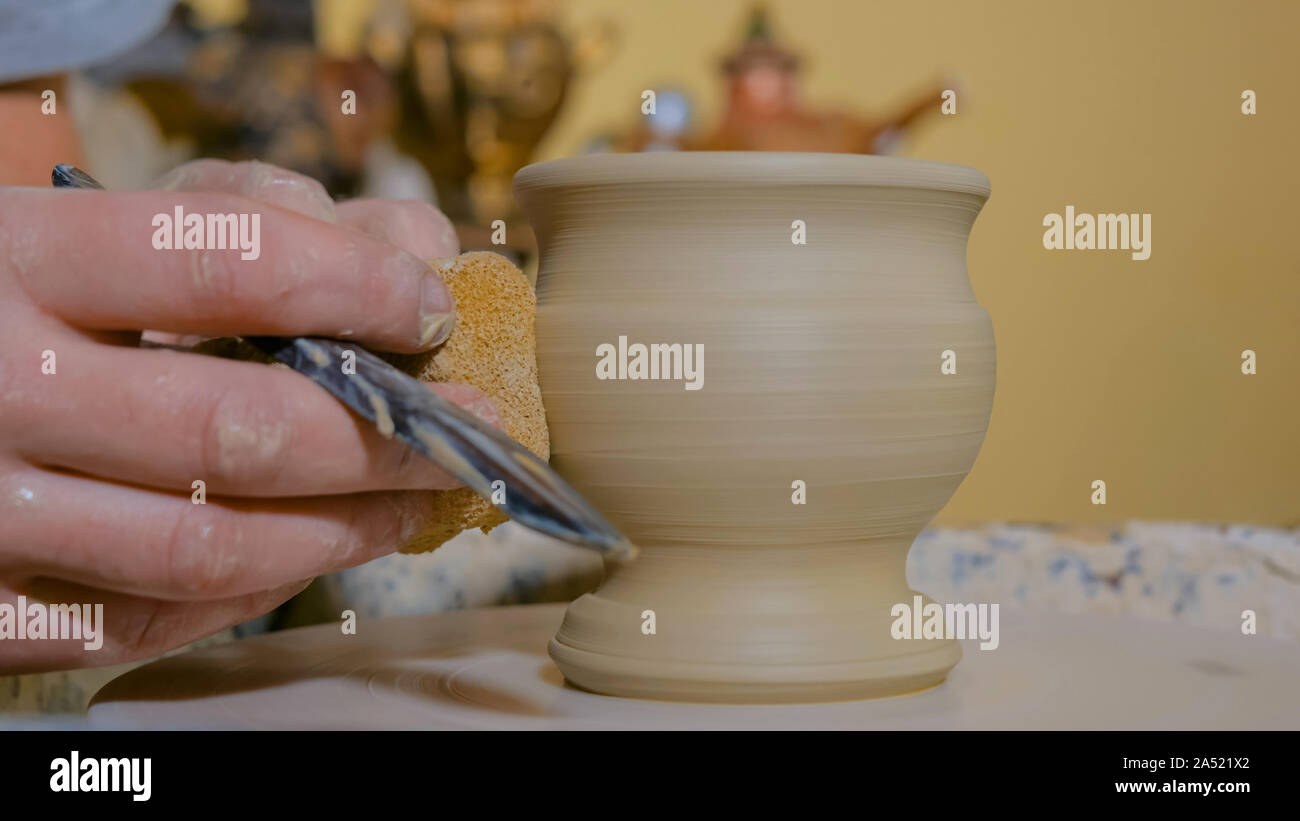Professional potter tazza di sagomatura con un attrezzo speciale nel laboratorio di ceramica Foto Stock
