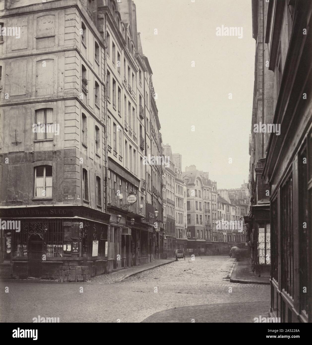 Rue de la Ferronnerie, c. 1865. Questo Marville fotografia è dalla sua serie su vecchie sezioni di Parigi prese durante il 1860s prima di Napoleone III e del Barone Haussmann tagliare grandi boulevards attraverso di loro. Marville documentario raggiunto la perfezione con precisione di rendering dei materiali, prospettiva esatta, interessanti forme e luminose le ombre. Egli preferisce lavorare su nuvoloso, giorni di pioggia quando la luce diffusa e scintillanti di acciottolato ha dato il massimo della gamma di tonalità e di dettaglio. Questa bella foto porta una quieta dignità alla vecchia strada. Foto Stock