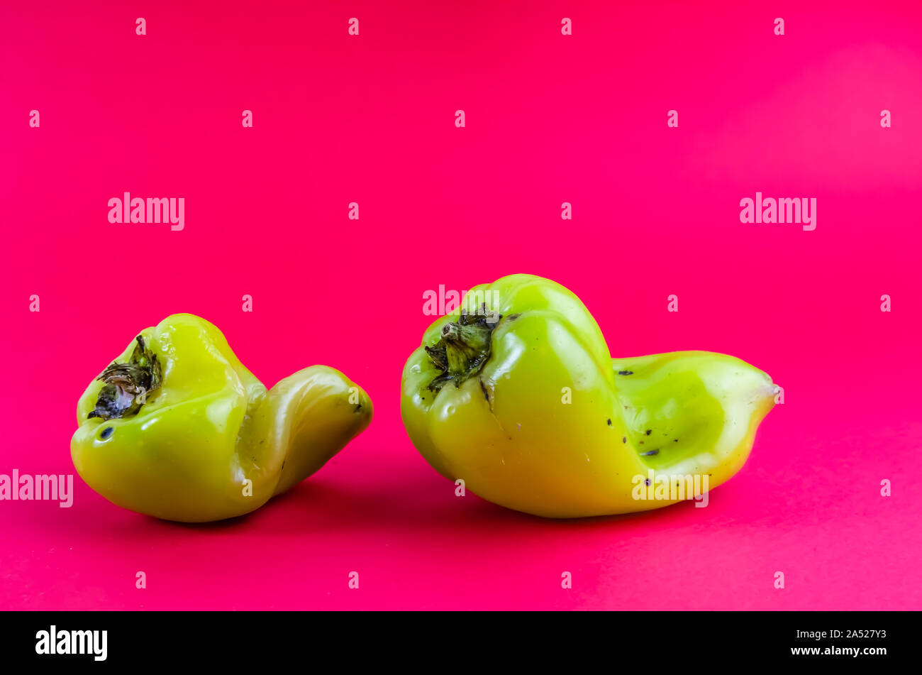 Brutto cibo. Il pepe verde su uno sfondo rosso. spazio copia Foto Stock