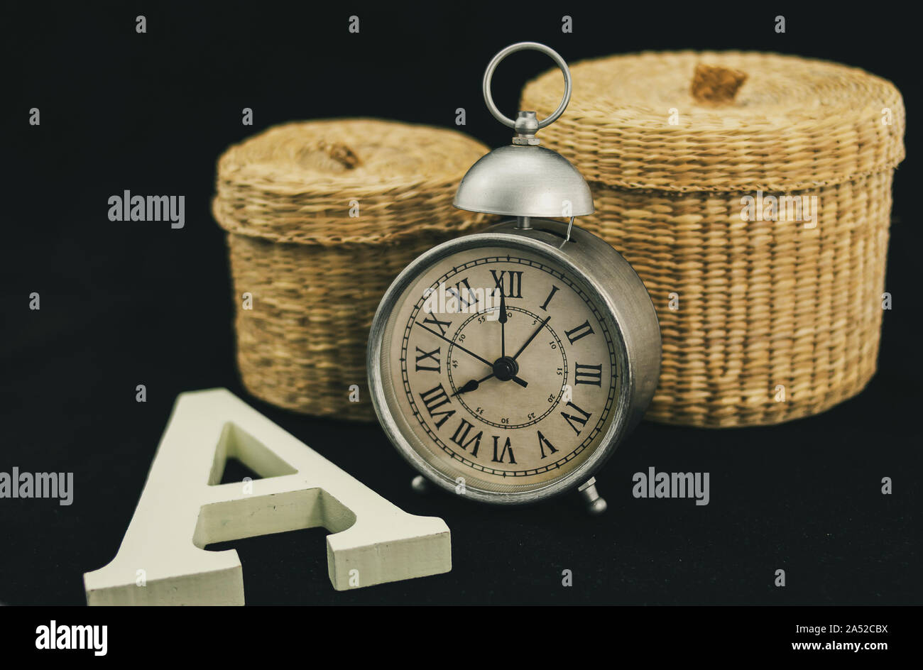 Orologio sveglia con due scatole di vimini e una lettera A maiuscola in bianco opaco e legno corporeo Foto Stock