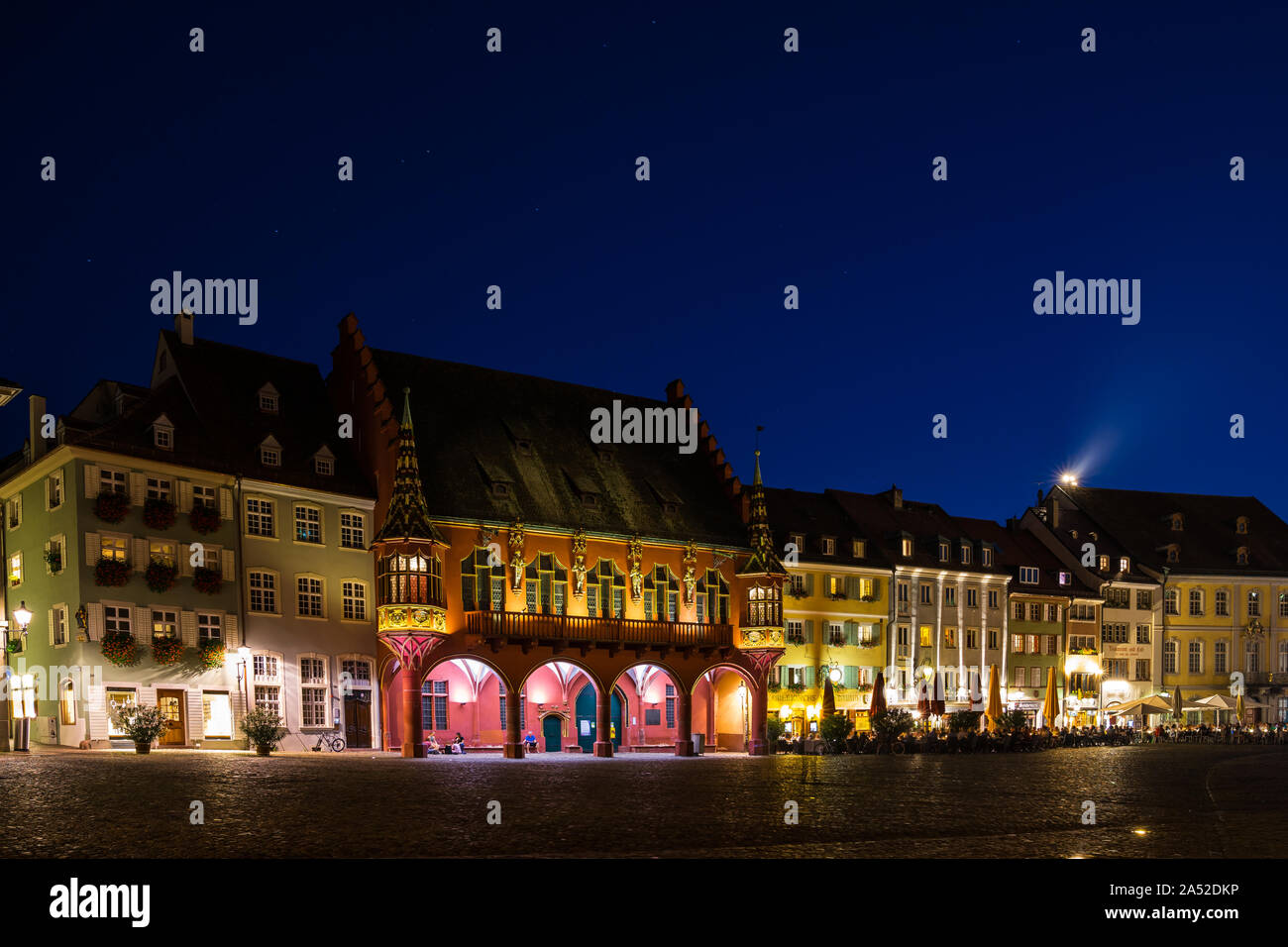 Freiburg im Breisgau, 30 agosto 2019, molte persone godendo calda notte d'estate nella città vecchia sulla famosa piazza della cattedrale accanto al vecchio magazzino bu Foto Stock