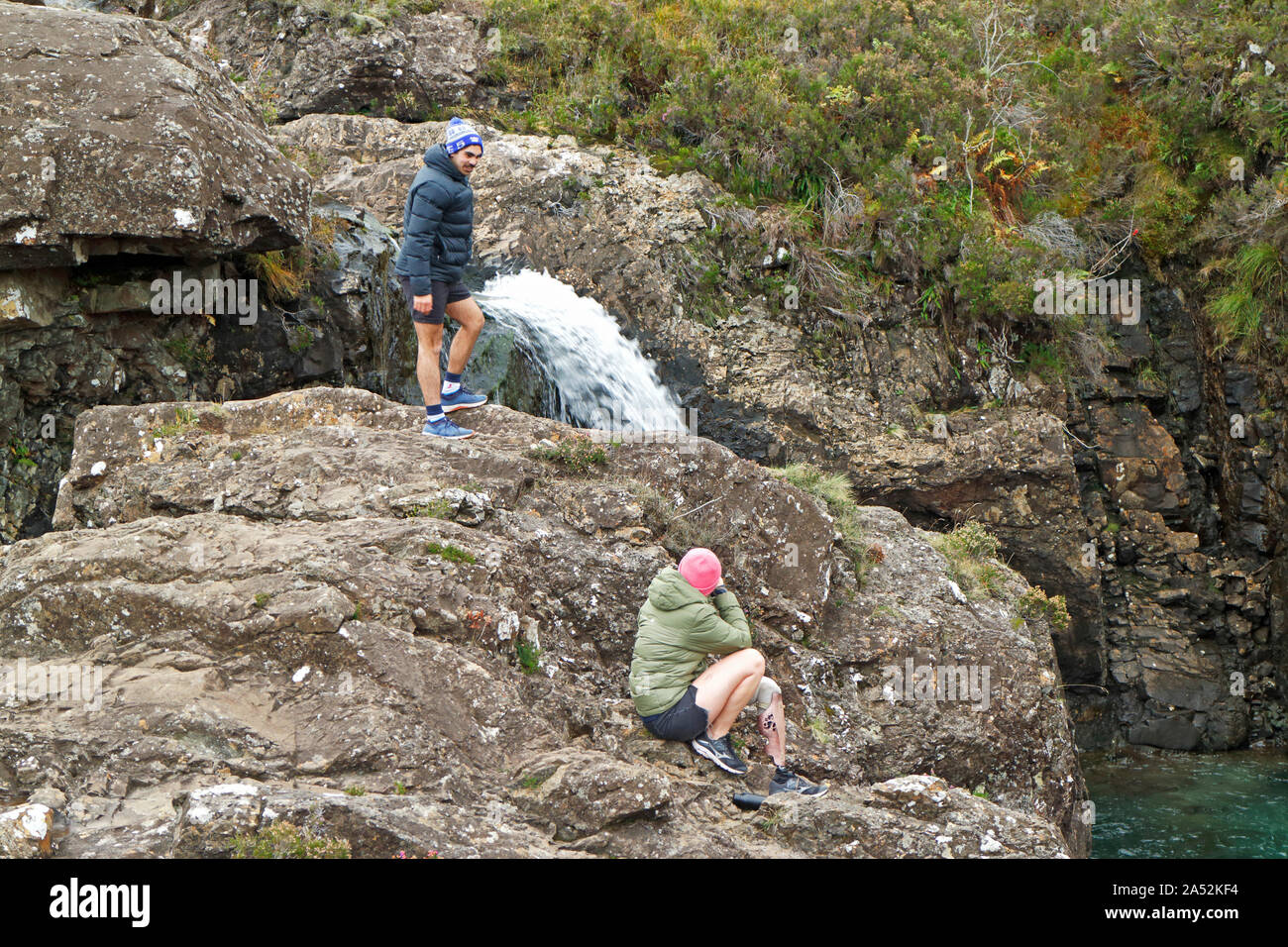 Due persone da una cascata sulle rocce al pool di Fairy, Isola di Skye in Scozia, Regno Unito, Europa. Foto Stock
