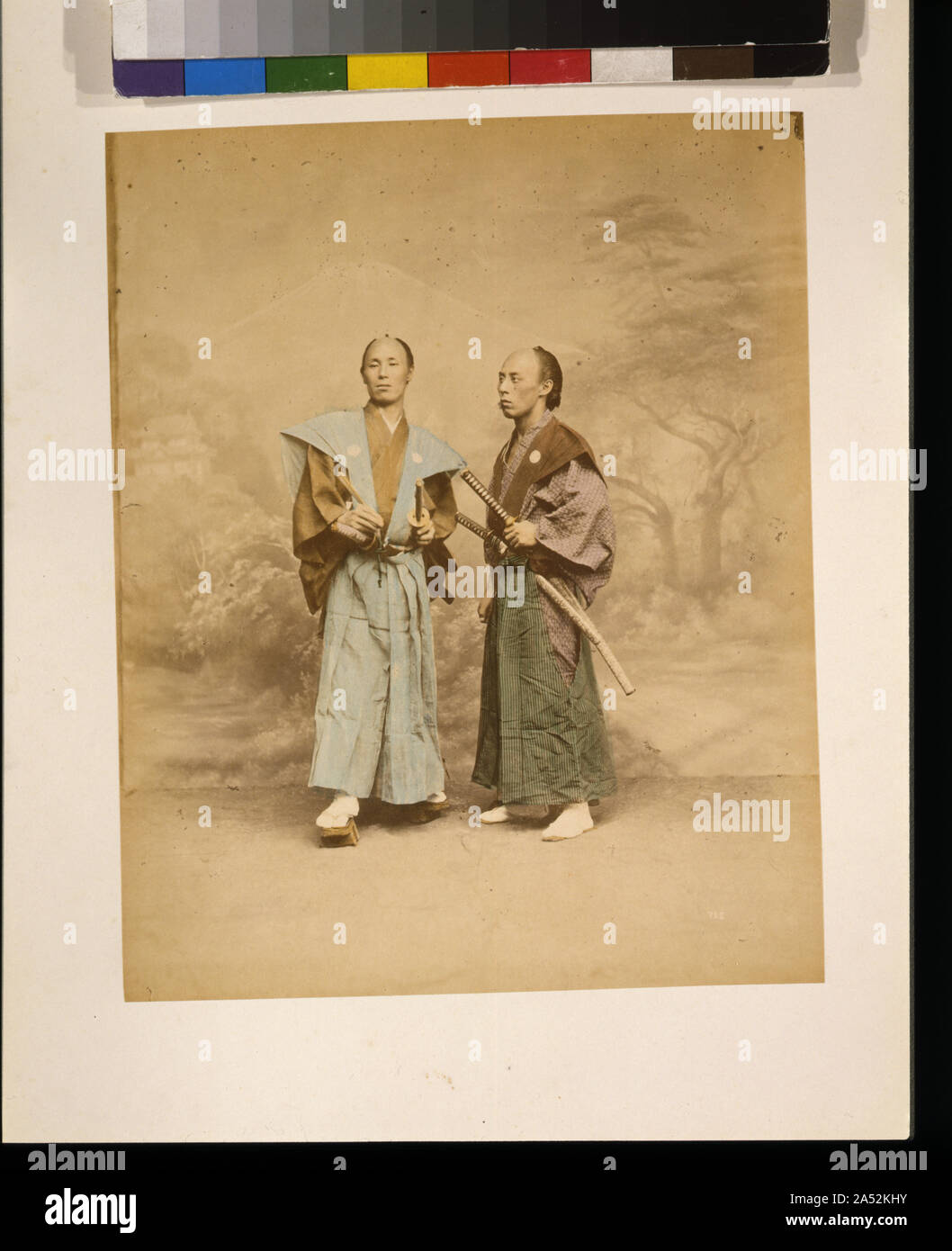 Due uomini giapponesi, eventualmente samurai, a piena lunghezza ritratto in studio con sfondo, in piedi, uno rivolto verso la parte anteriore e l'altra rivolta verso sinistra, ciascuno con due spade Foto Stock