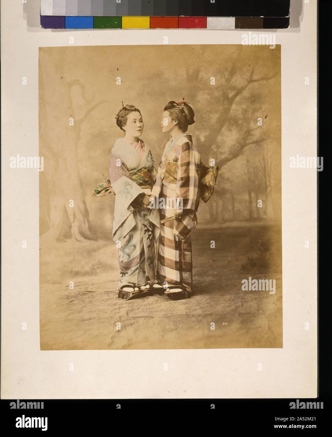 Due donne giapponesi e a piena lunghezza ritratto in studio con sfondo, in piedi, affacciati, tenendo le mani Foto Stock