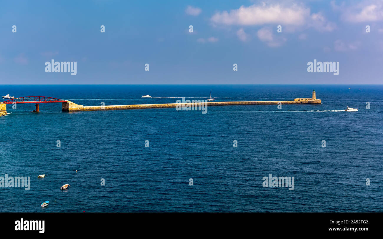 Red St Elmo ponte in acque turchesi del mar Mediterraneo acqua, che conduce dal foreshore del Forte Sant'Elmo a La Valletta, Malta, il frangiflutti. Foto Stock