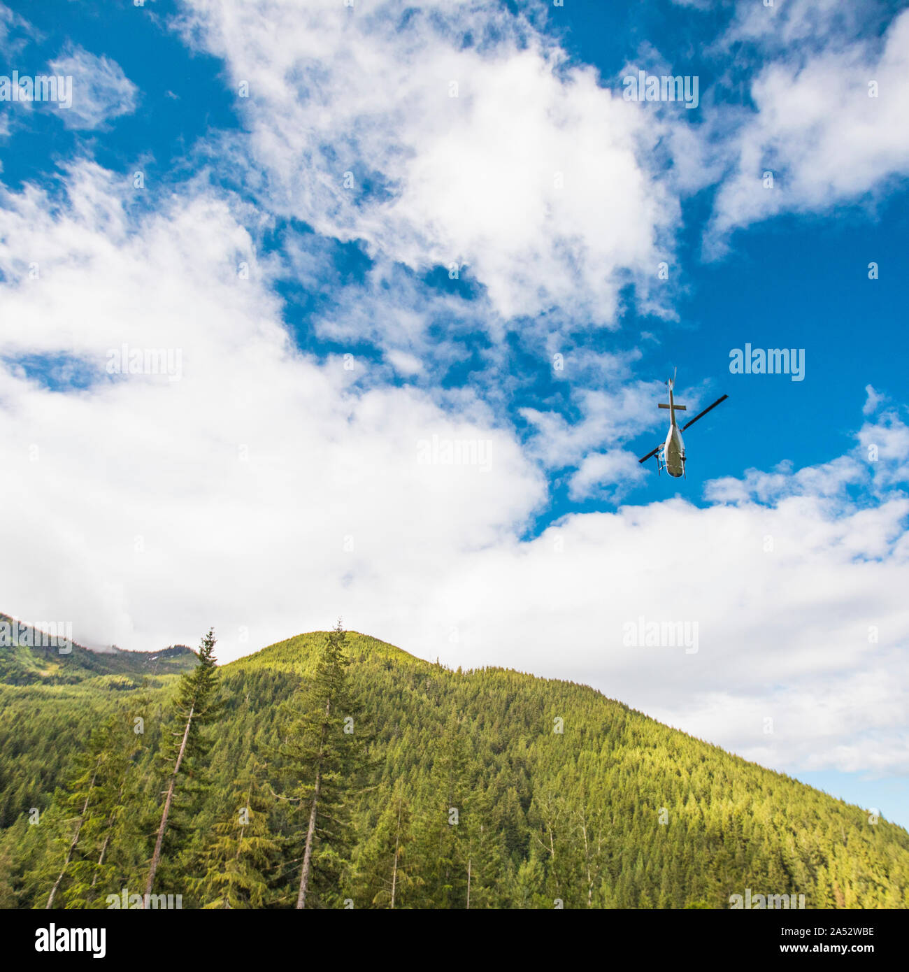 Un elicottero che vola attraverso le montagne su giorno d'estate. Foto Stock