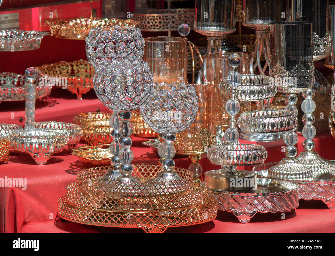 Vetro bicchieri di vino e ciotole con modelli di metallico sul bancone. Diffusione coperchio rosso sul pavimento. Foto Stock