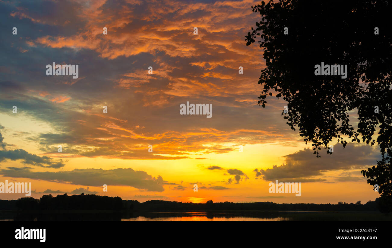 Bellissima scenic arancione tramonto in una nuvola su un lago in tarda serata Foto Stock