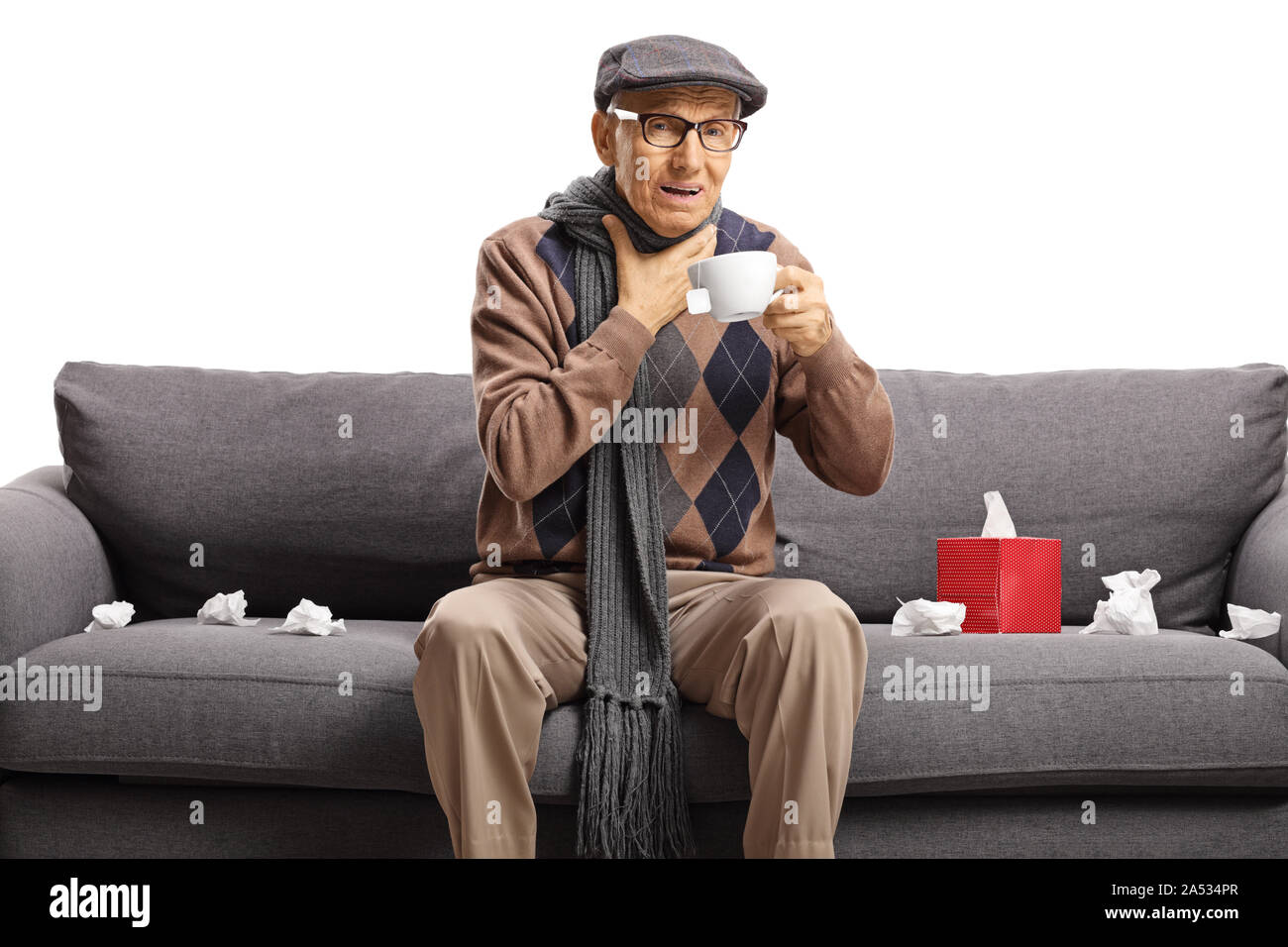 Uomo anziano con un mal di gola seduta su un divano e bere il tè isolati su sfondo bianco Foto Stock