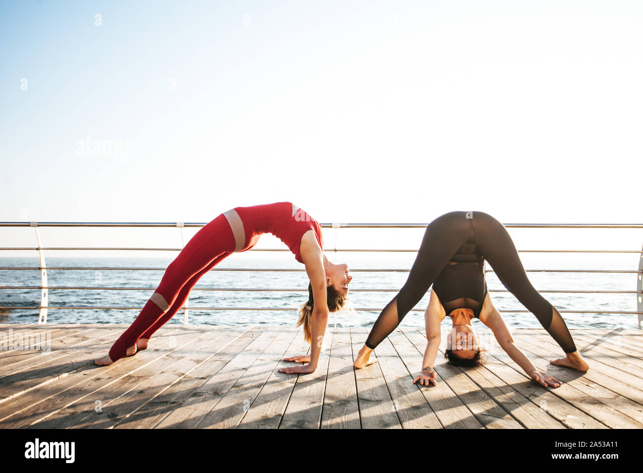 Vista laterale di due donne sportiva stretching capovolto mentre si pratica il pilates Foto Stock