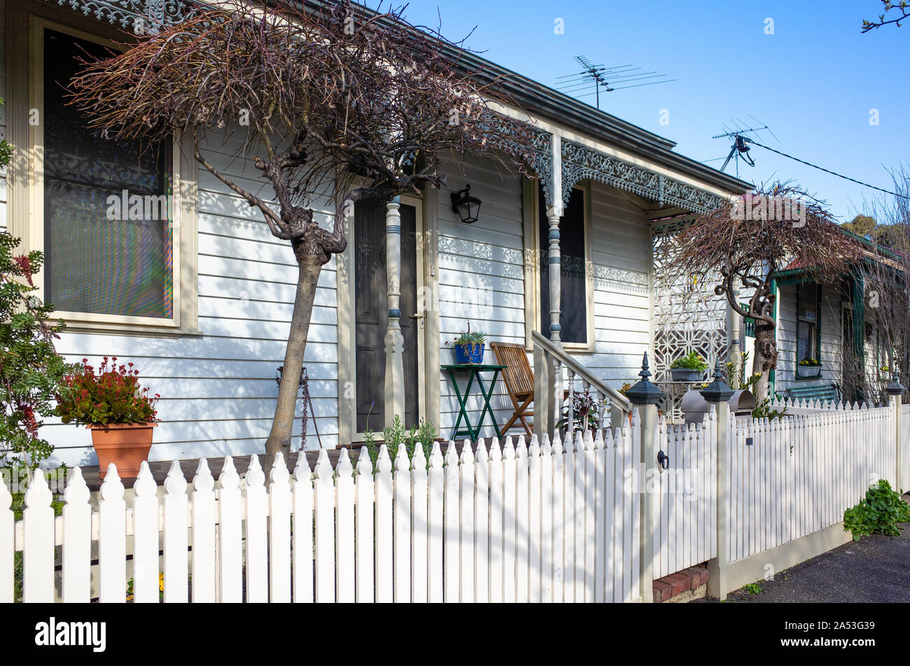 Casa per gli agenti atmosferici australiani con una recinzione per picchetti in legno. Una vecchia casa suburbana e un portico frontale con ghisa decorata di epoca vittoriana. Foto Stock