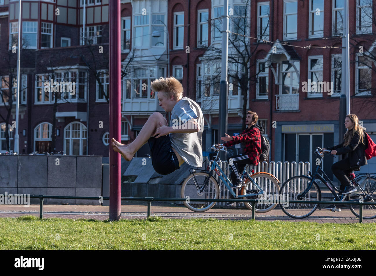 Amsterdam, Olanda, febbraio 25 2019 street flipping boy sul prato del Museumplein di Amsterdam nel suo shorts in una giornata di sole Foto Stock