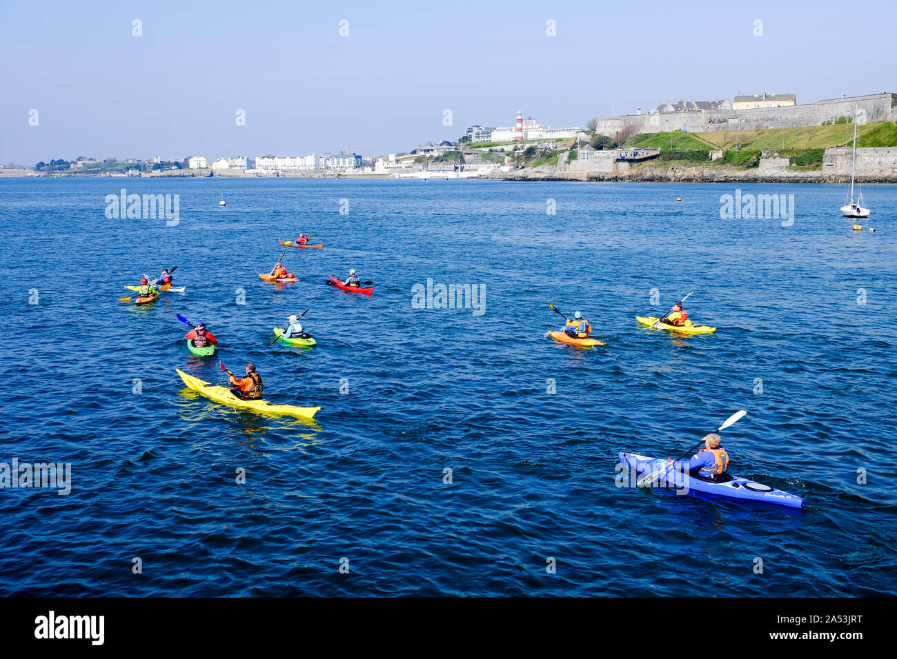 Canoe colorate in Plymouth Sound con la mitica Plymouth Hoe in background. Foto Stock
