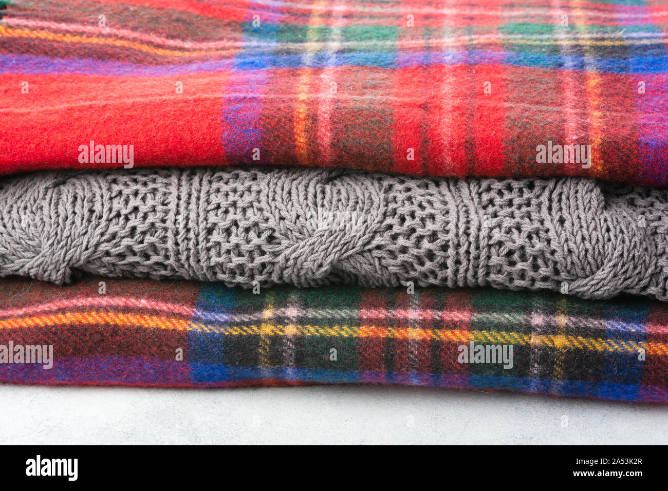 Pila di accogliente winter coperte di lana in tartan rosso, blu, grigio colori, il fuoco selettivo Foto Stock