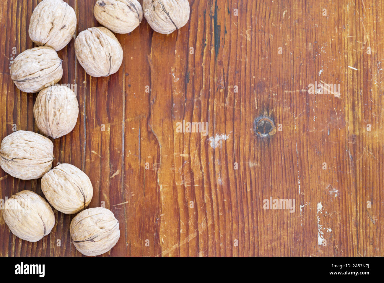 Noci comuni con guscio sul lato di un vecchio addolorato Sfondo legno Foto Stock