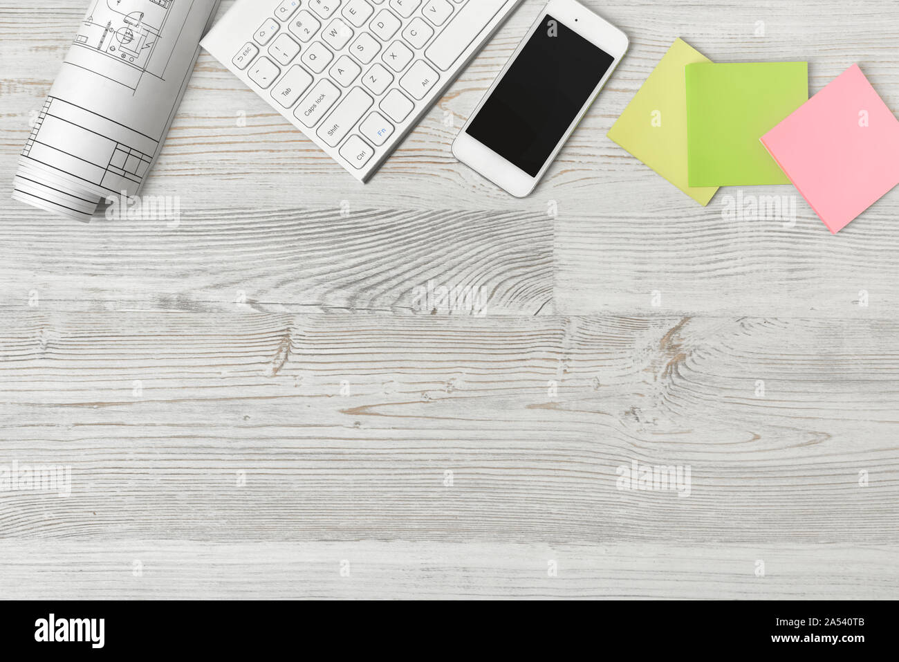 Vista superiore del luogo di lavoro con rotolo di carta, tastiera, smartphone e adesivi sul tavolo di legno Foto Stock