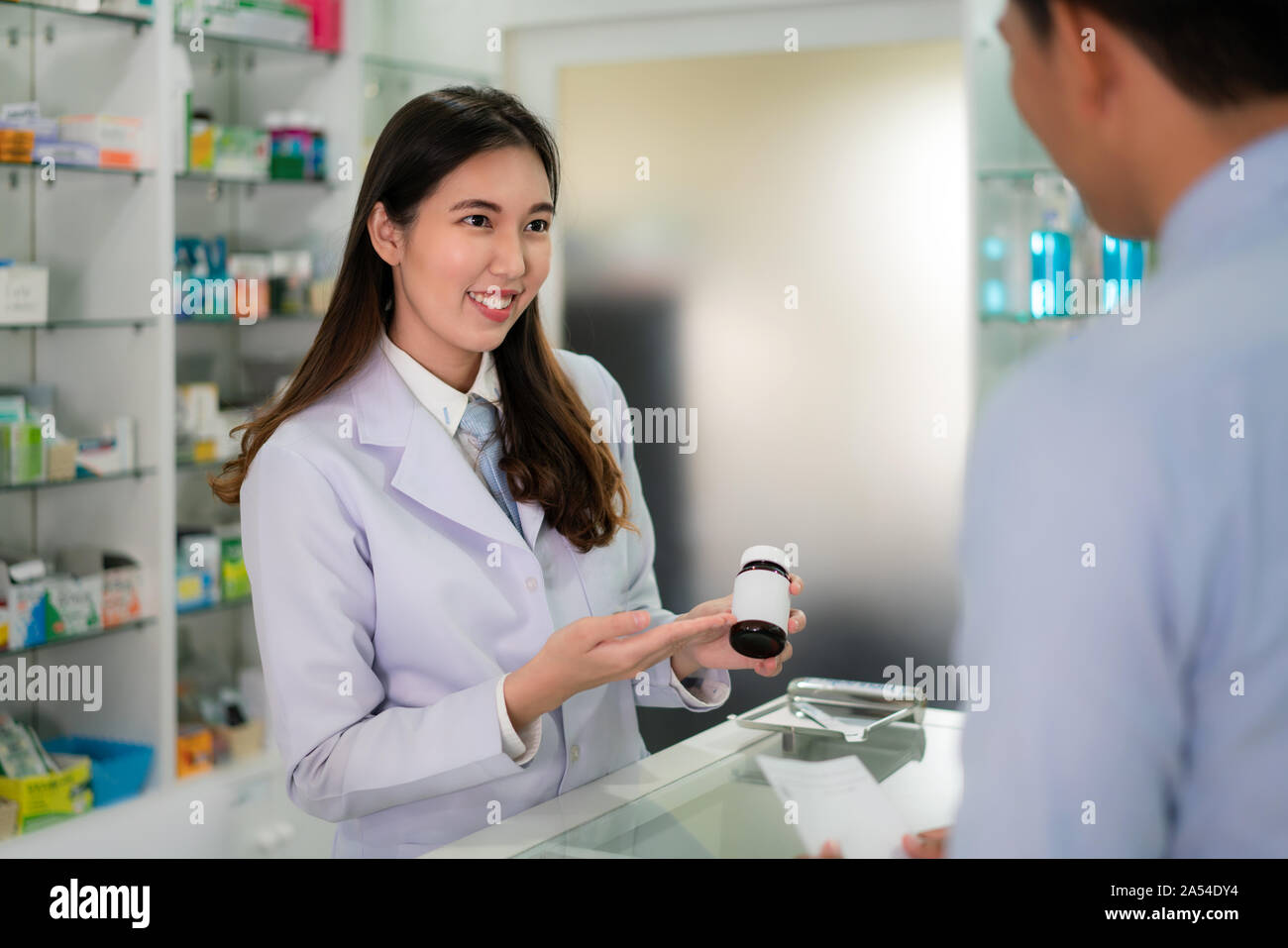 Fiducioso asiatici femmina giovane farmacista con un bel sorriso amichevole e spiegando la medicina per il suo cliente in farmacia farmacia. Medicina, PHA Foto Stock
