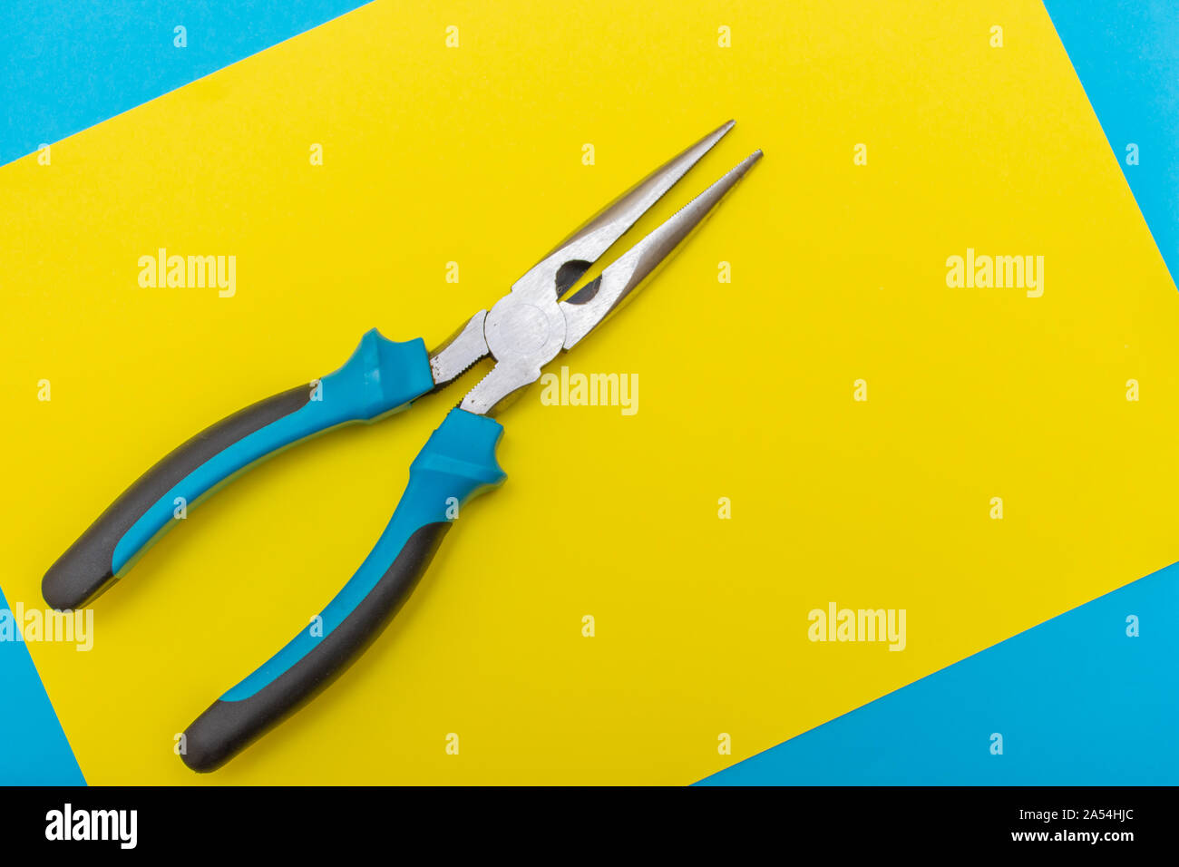 Miglioramento di casa: pinza su un blu e giallo piatto sfondo laici con copia spazio. Foto Stock