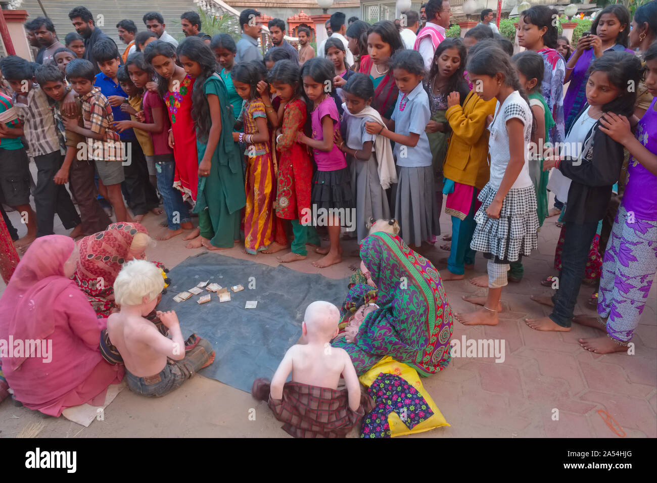 I membri di un indiano estesa famiglia Albini richiedono donazioni in Udipi, Karnataka, India, circondato e fissavano da una folla di gente del posto Foto Stock