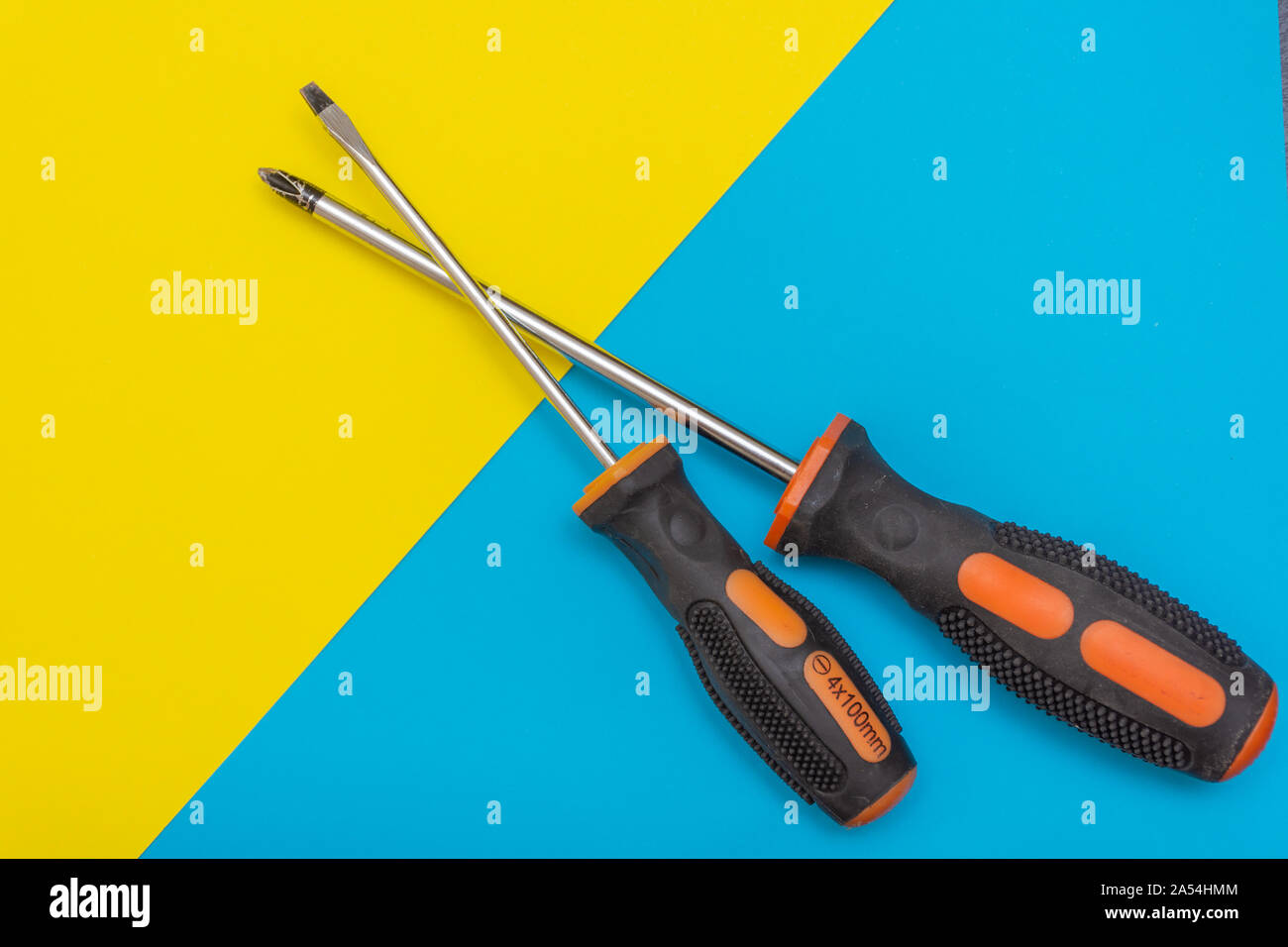 Miglioramento di casa: due cacciaviti Philips (e) scanalato su un blu e giallo piatto sfondo laici con copia spazio. Foto Stock