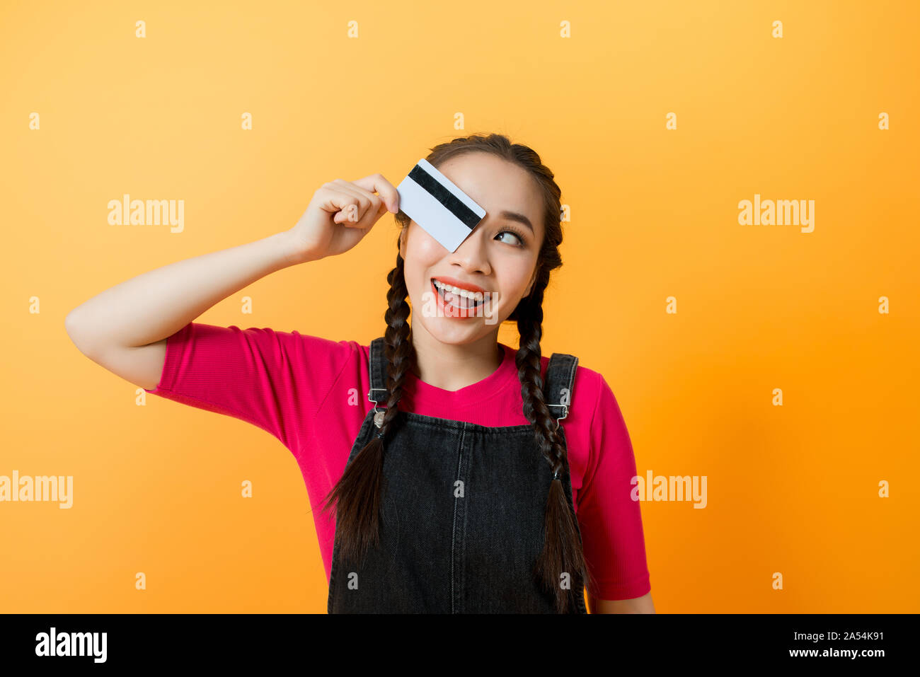 Giovani sorridente bella donna asiatica presentando la carta di credito in mano che mostra la fiducia e la fiducia per effettuare il pagamento Foto Stock