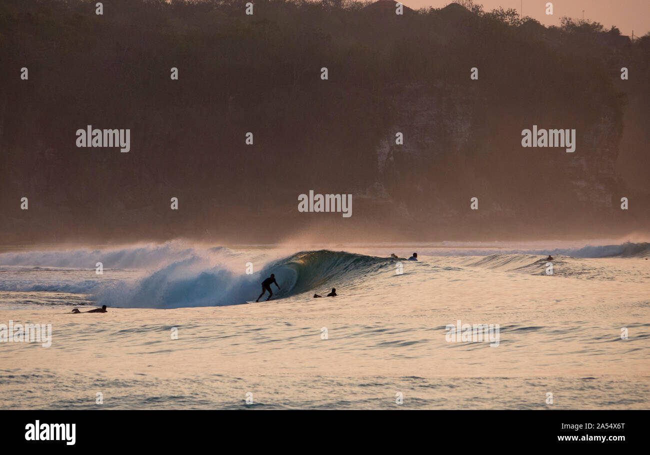 Surfer in sella ad una barriera corallina poco profonda wave a Bingin sulla penisola di Bukit, Bali Foto Stock