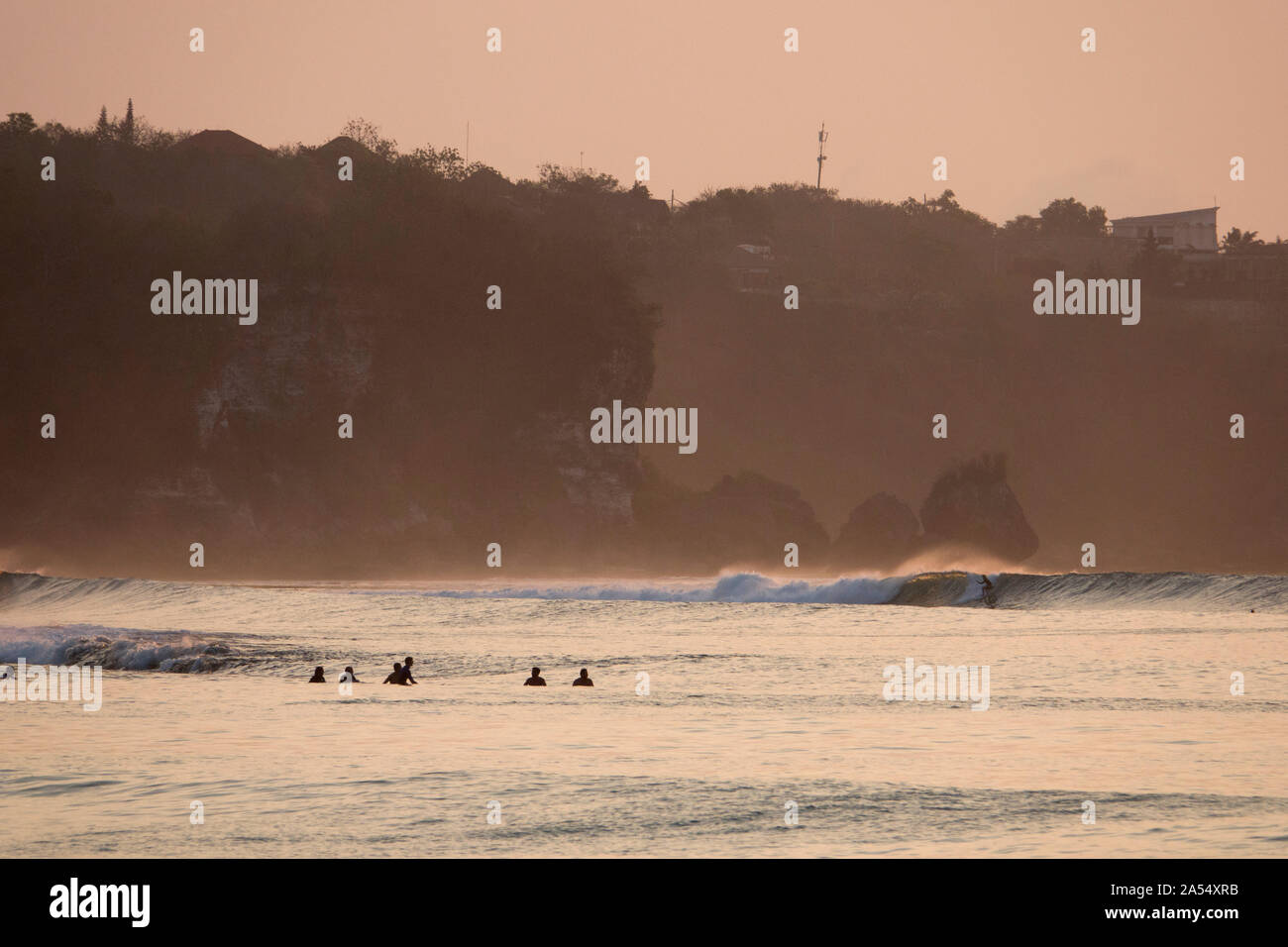 Surfer in sella ad una barriera corallina poco profonda wave a Bingin sulla penisola di Bukit, Bali Foto Stock