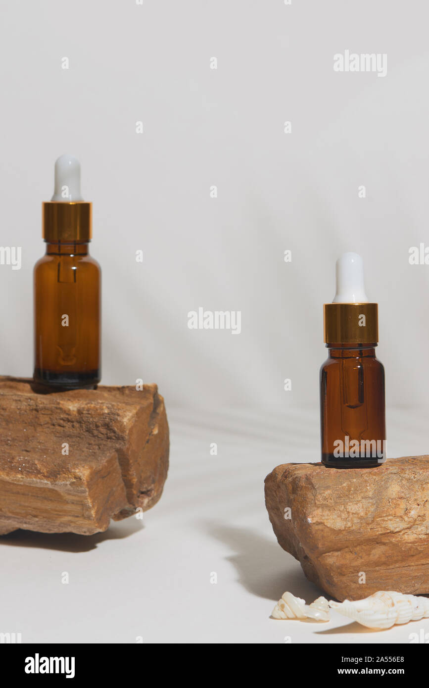 Siero o di olio essenziale in stile tropicale con lasciare, rocce, mare sehlls su sfondo bianco. Prodotto di bellezza concetto. Foto Stock