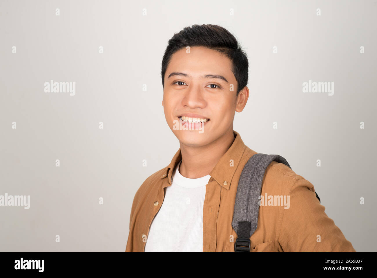 Ritratto di bello studente asiatico zaino porta isolata su sfondo bianco Foto Stock