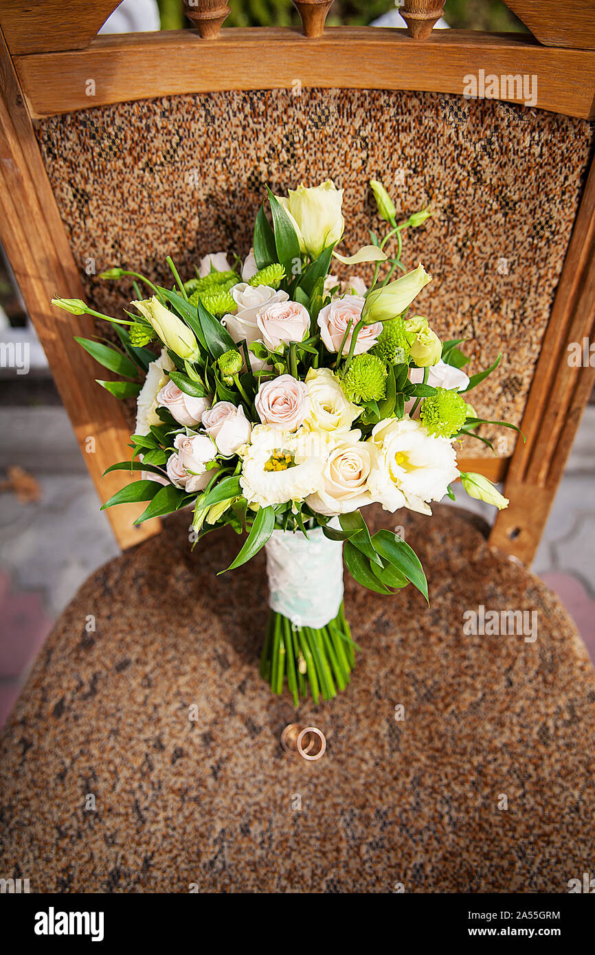 Anello e bouquet di fiori diversi su una sedia Foto Stock