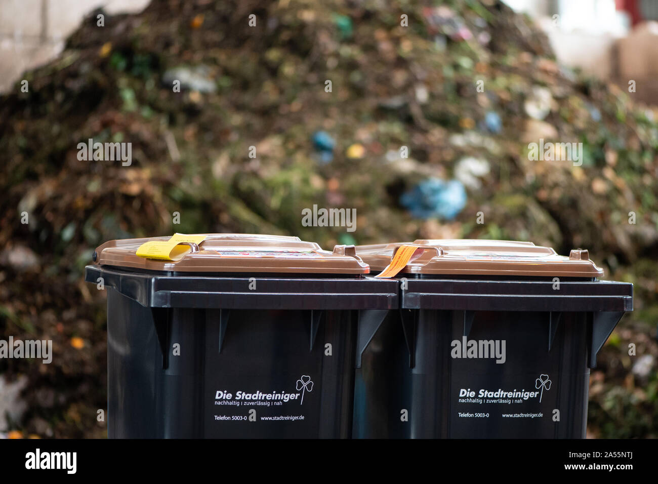 Kassel, Germania. Xviii oct, 2019. Due scomparti biowaste sostare davanti a un mucchio di composto a Kassel rifiuti da impianti di energia. A partire da giugno 2018, i valori limite per le impurità in biowaste sono state serrate in modo significativo. Sacchetti di plastica, imballaggio e gli altri rifiuti residui mettono in pericolo il riciclaggio di rifiuti organici in Kassel. Credito: Swen Pförtner/dpa/Alamy Live News Foto Stock