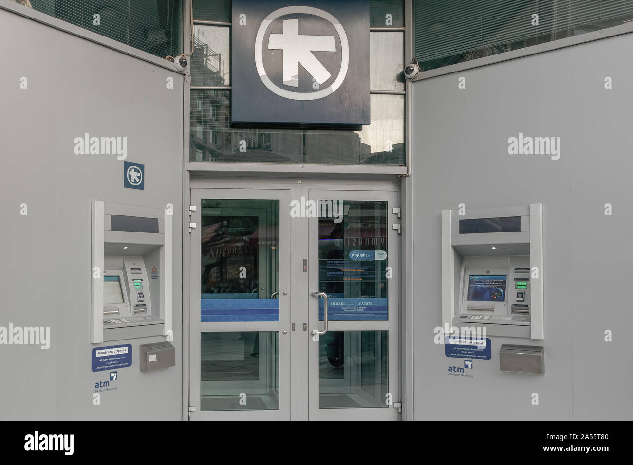 Banca greca macchine ATM e ingresso. Ingresso Sicuro & 24 ora le macchine di contanti al di fuori del ramo di Alpha Bank la Grecia con il logo della banca a Salonicco Grecia. Foto Stock