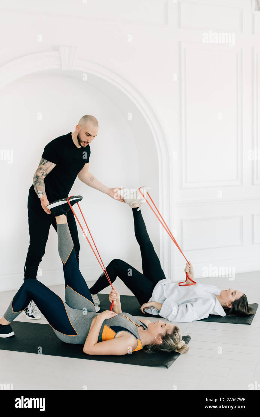 Istruttore di Fitness insegnamento le donne che utilizzano la banda di resistenza in studio Foto Stock
