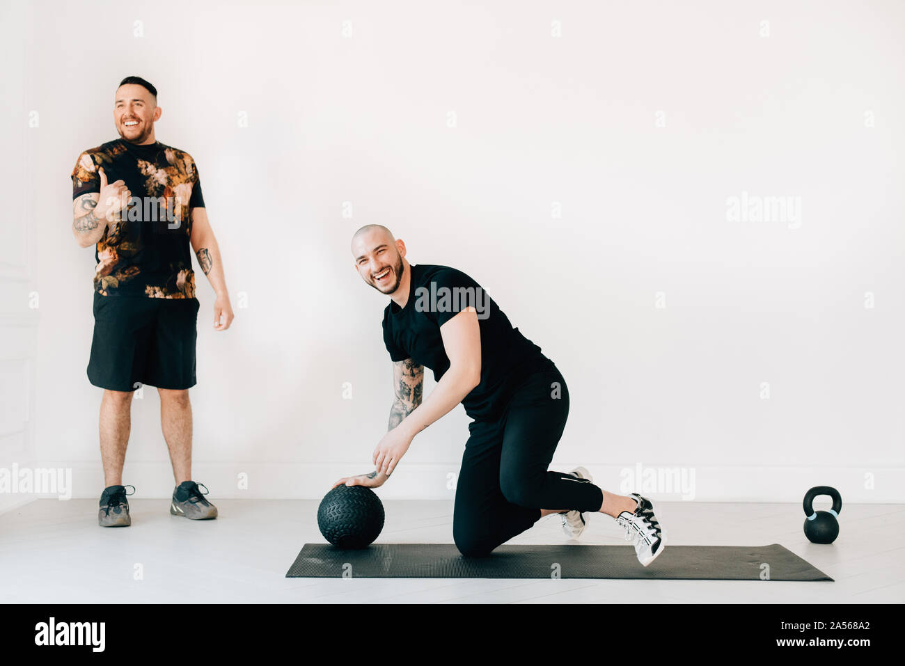 L uomo dando pollice fino a istruttore di fitness in studio Foto Stock
